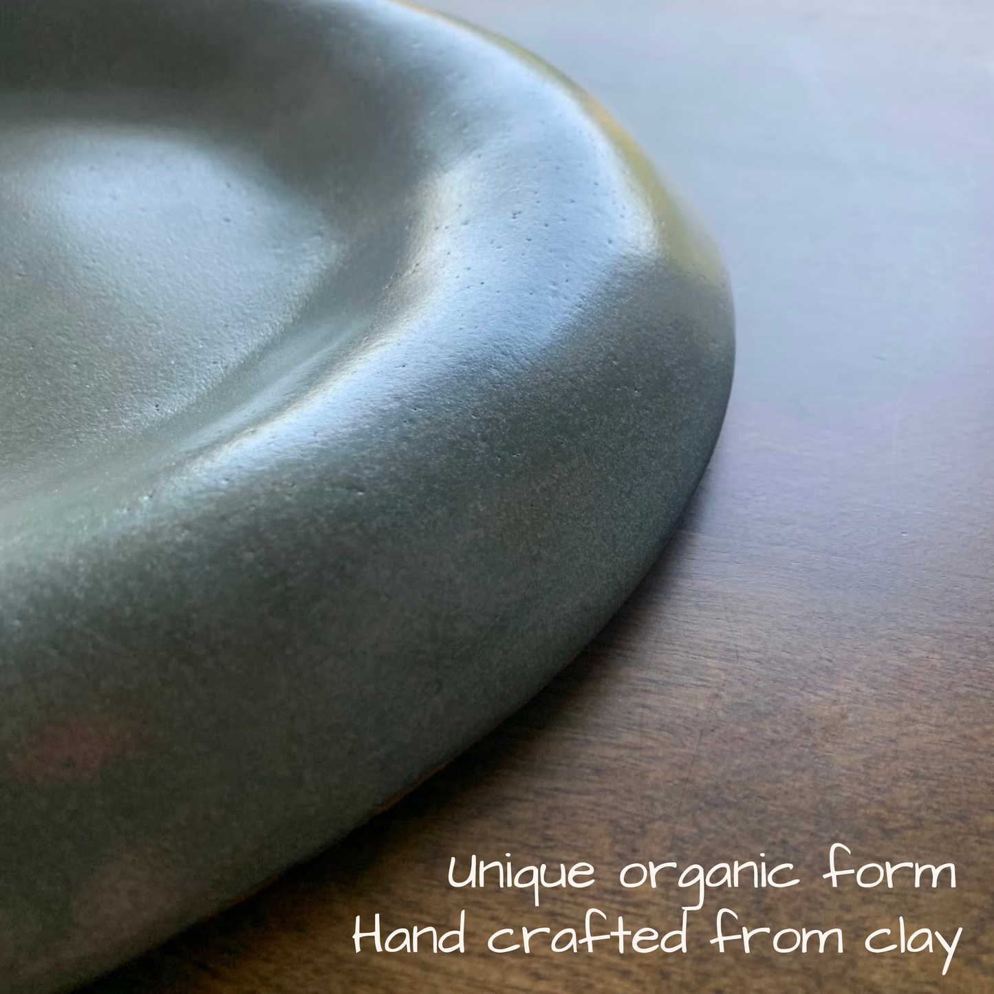Handcrafted ceramic dish on a wooden surface with text describing its unique organic form.