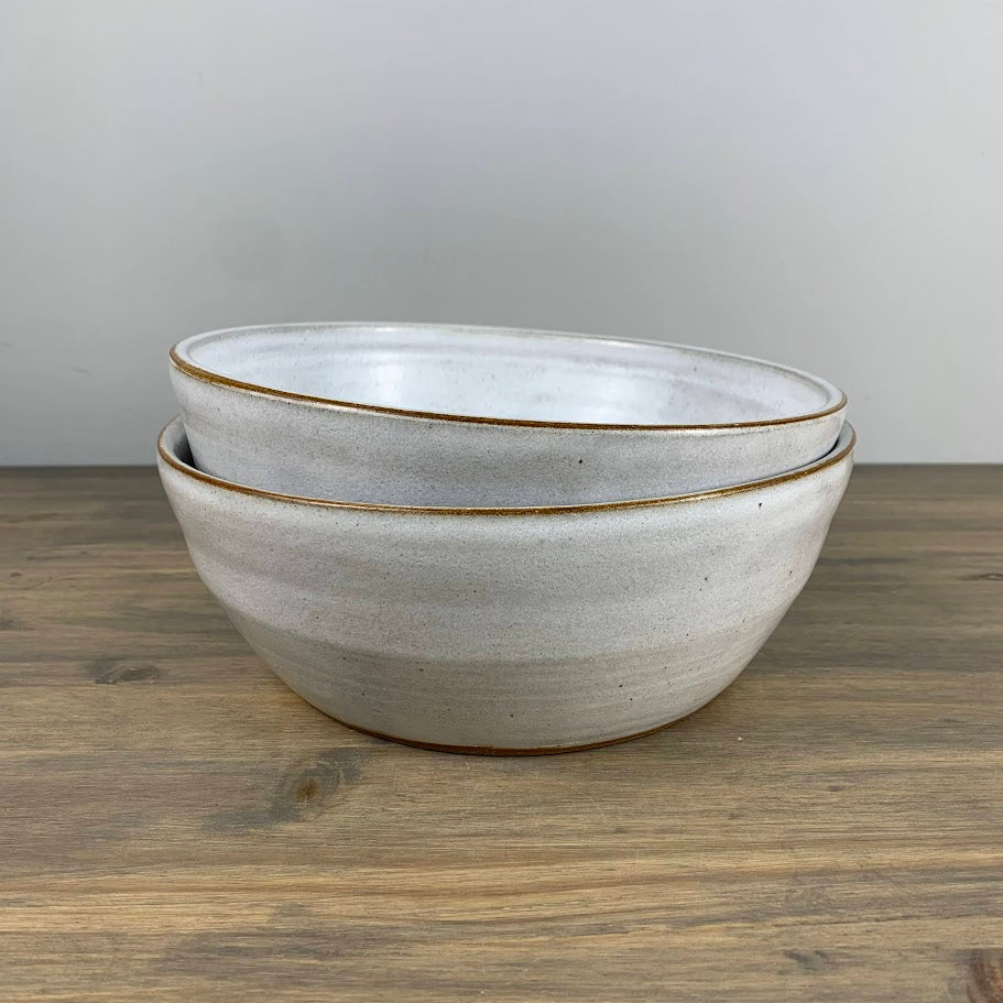 Two ceramic bowls stacked on a wooden surface with a gray background