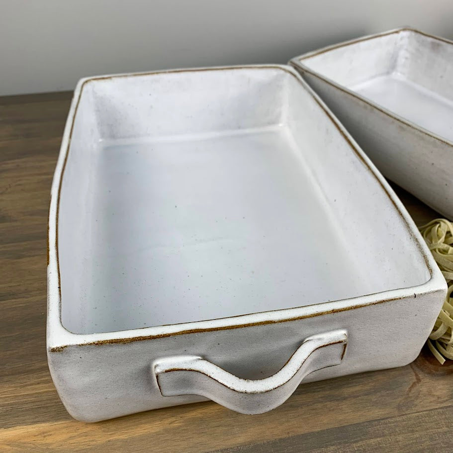 White rectangle, shallow ceramic dish with handle on a wooden surface