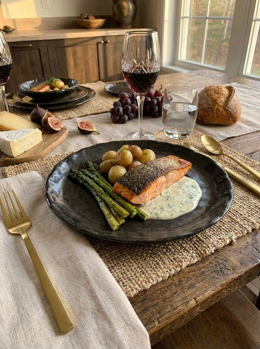 Dinner table setting with salmon dish, wine, and fruits in a home kitchen.