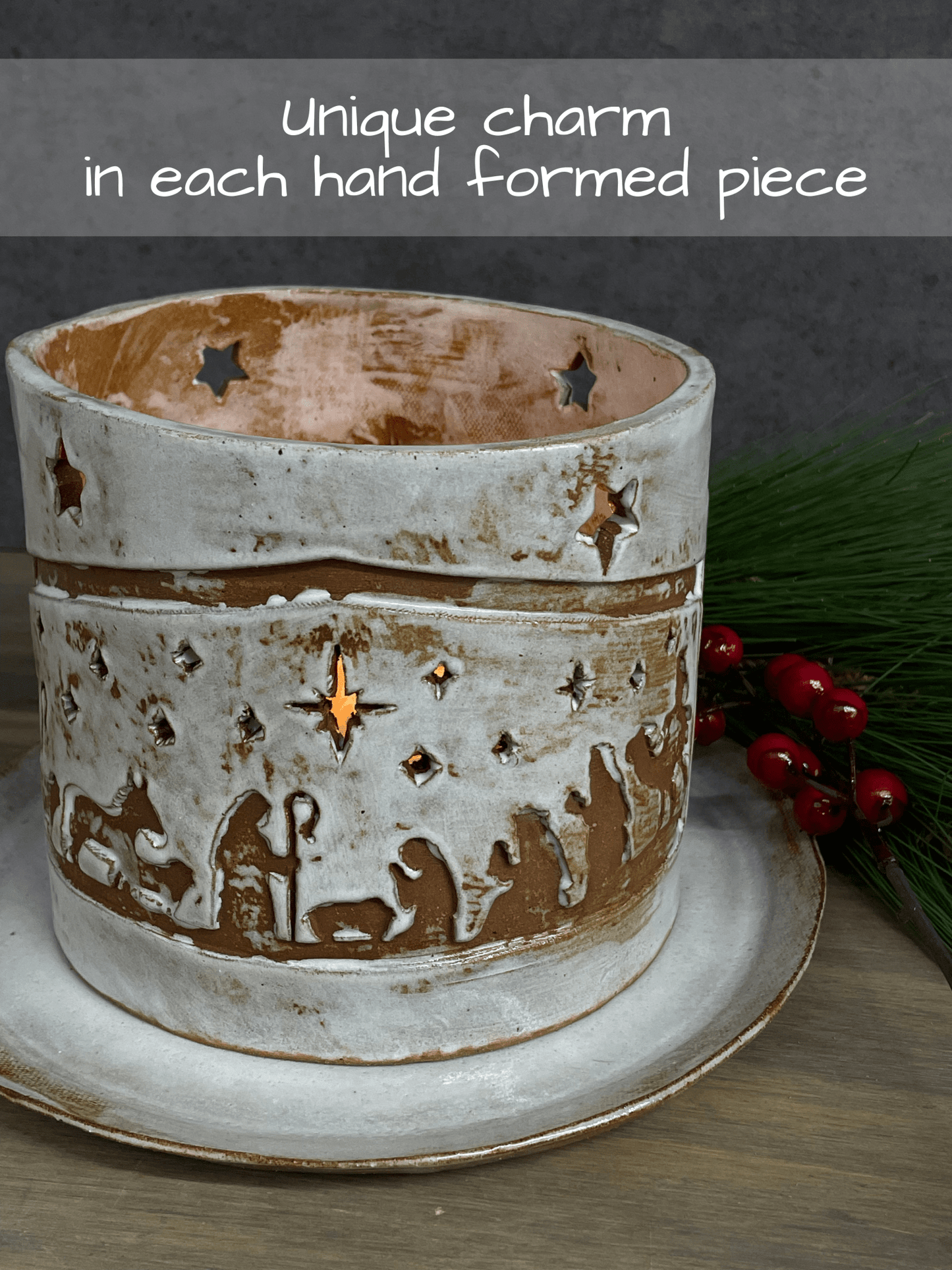 Ceramic lantern with nativity design on a wooden surface with text 'Unique charm in each hand formed piece'.