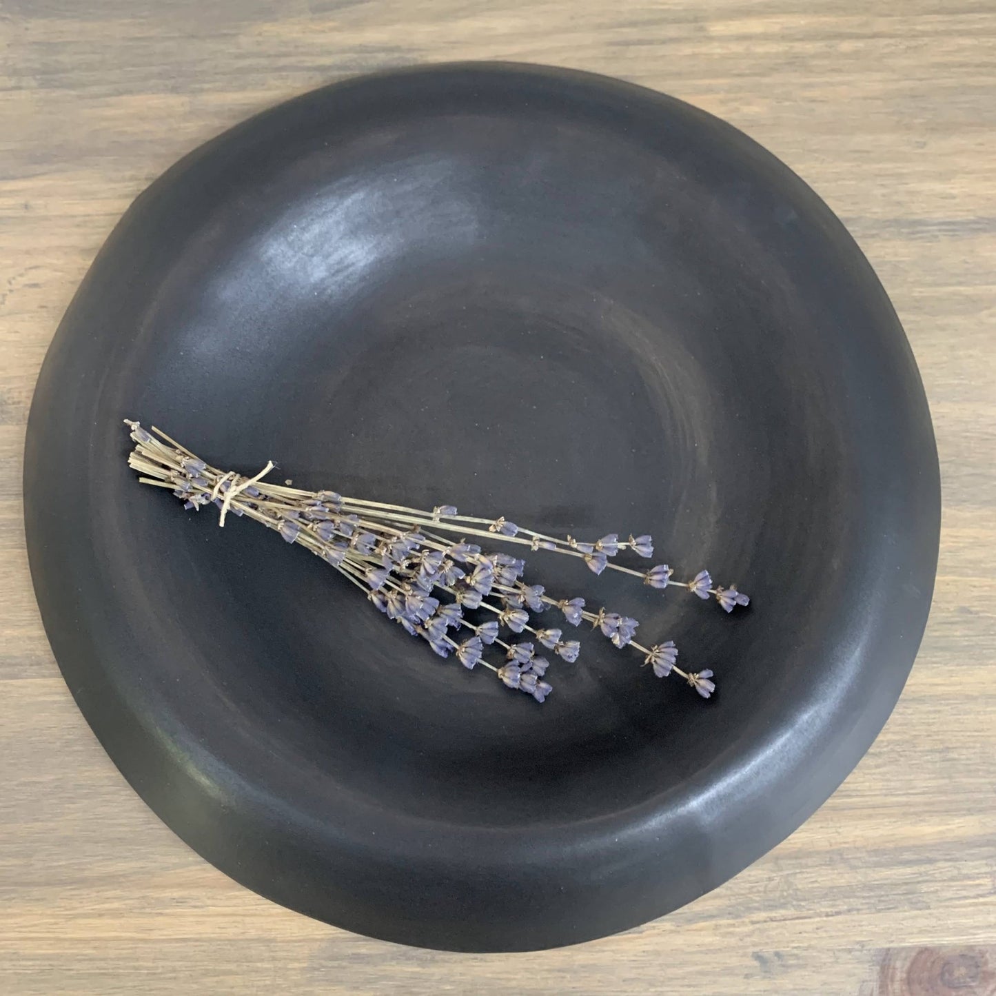 Black bowl with dried lavender on a wooden surface