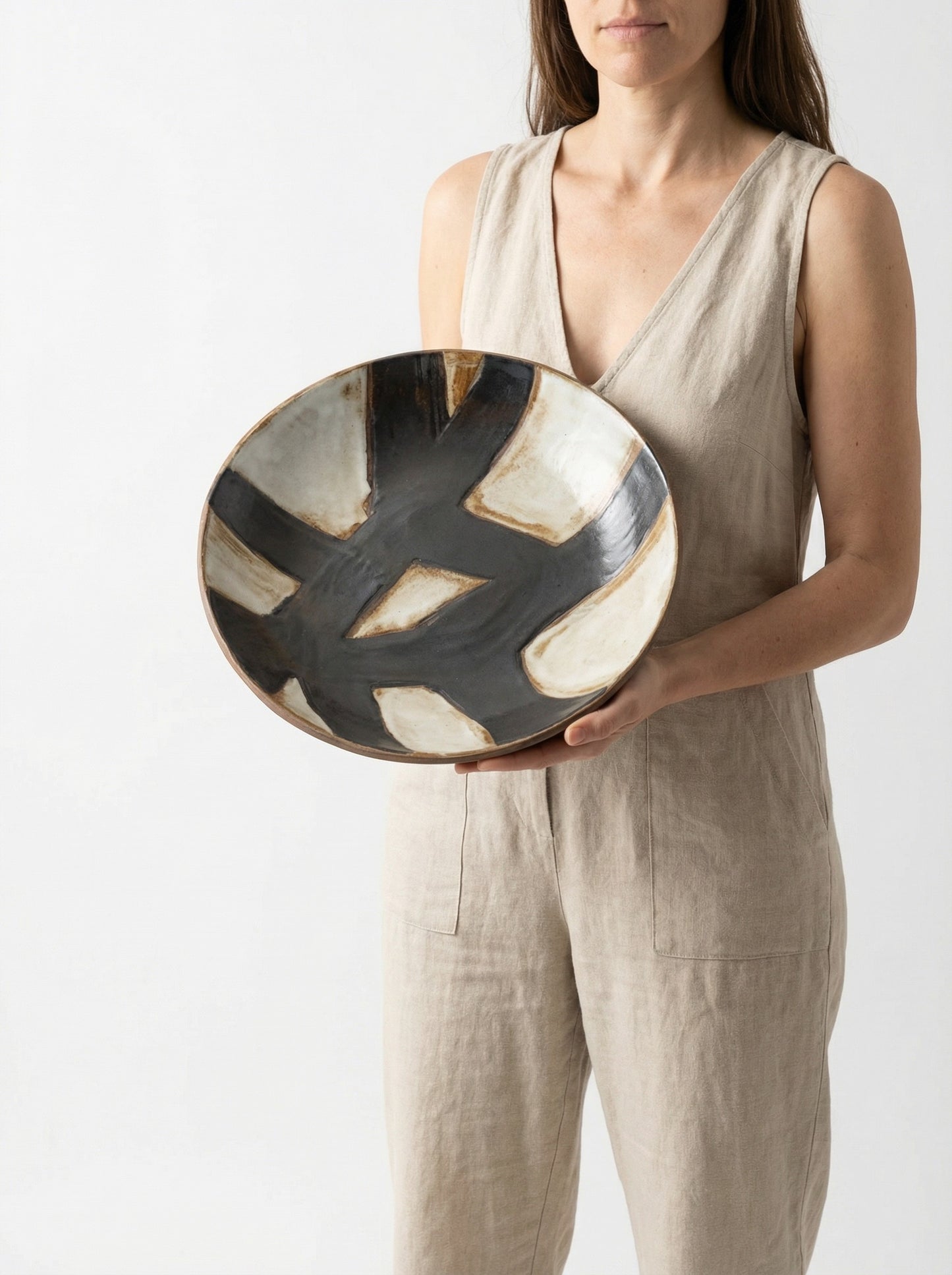 Person holding a ceramic art bowl with abstract design on a plain background