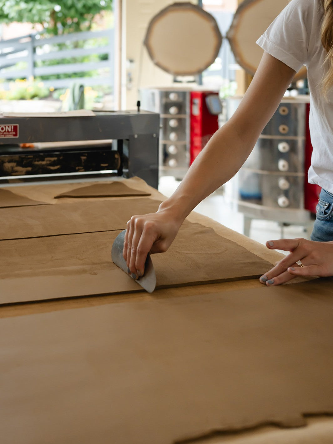 Person smoothing a clay surface with a tool in a ceramic studio setting