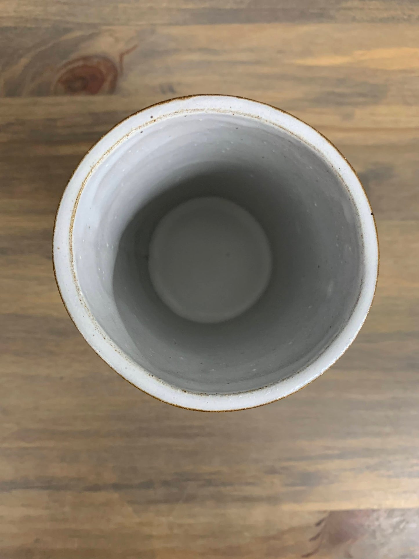 top view looking into a white pottery vase on a wooden surface