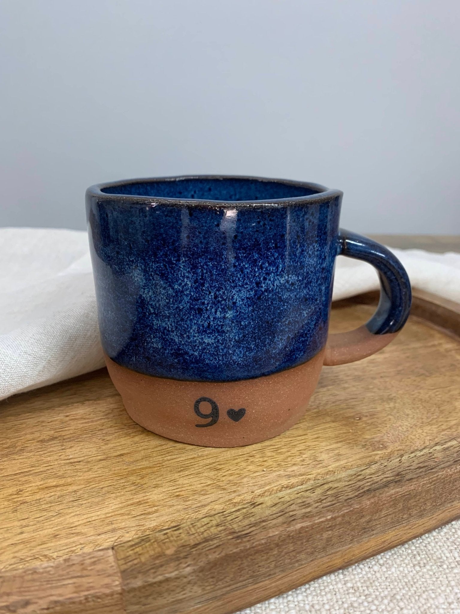 Blue ceramic mug with a heart and number on a wooden surface