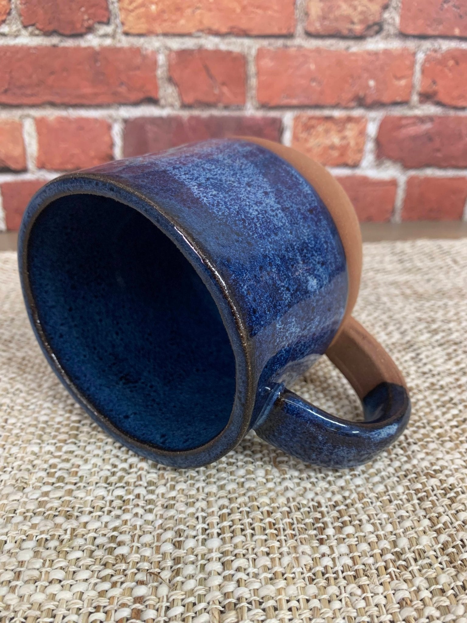 Blue ceramic 9th anniversary mug on a textured surface with a brick wall background