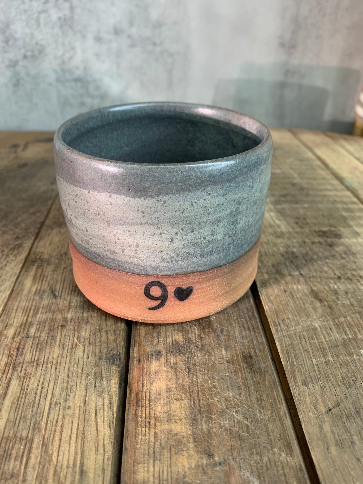 a gray pottery cup with a 9 and a heart printed on the front