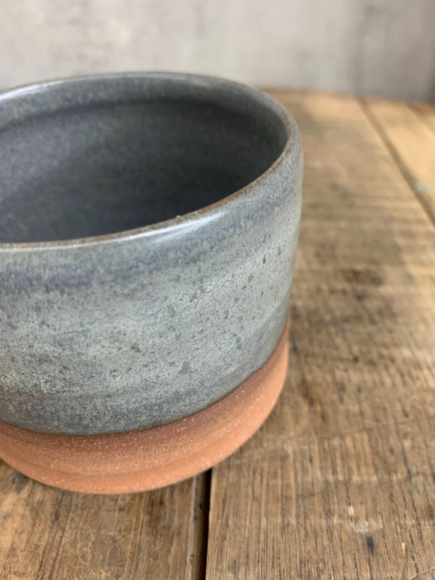 gray Ceramic cup with gray top and raw clay base on a wooden surface