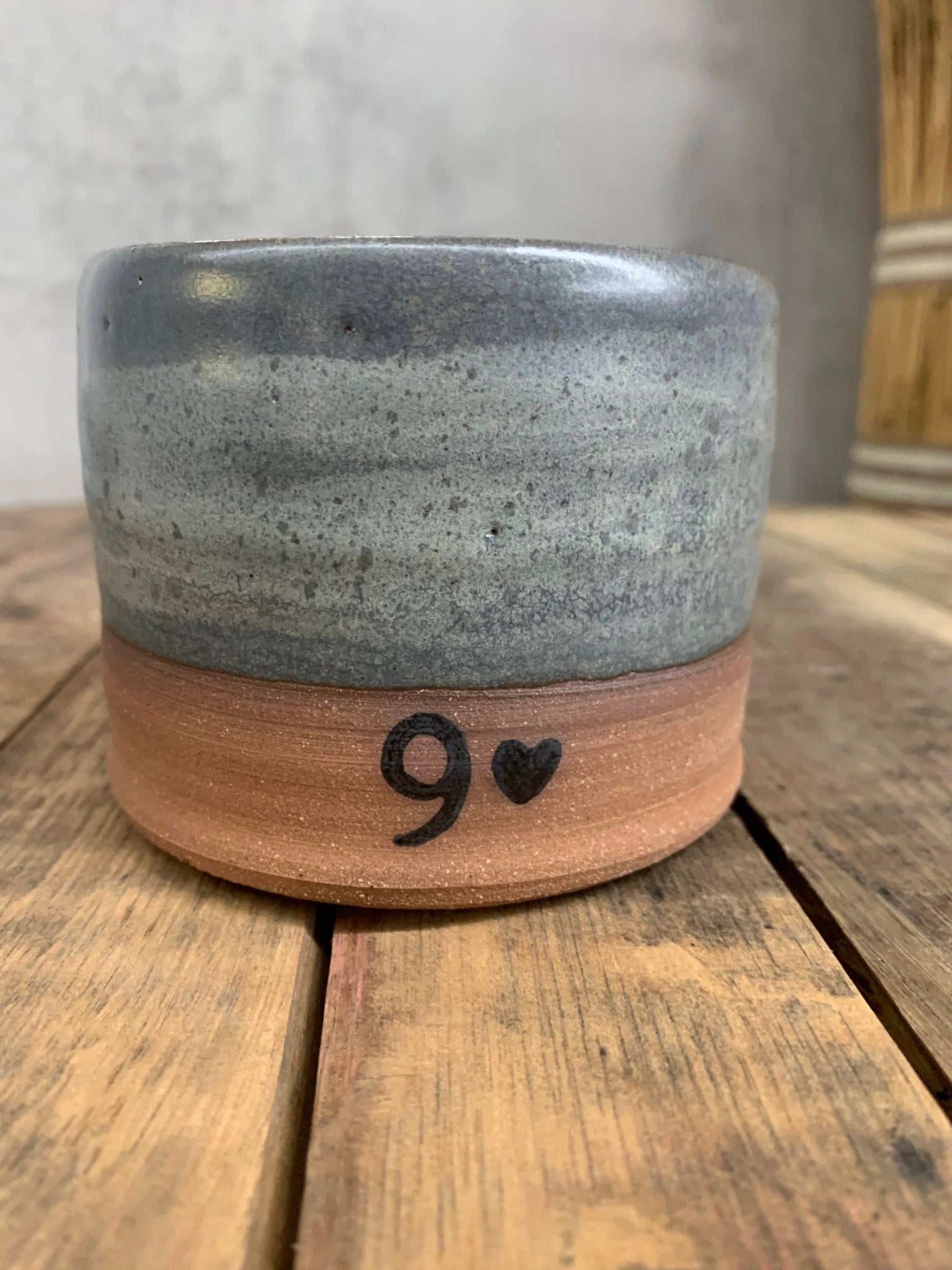 Ceramic pottery cup with a speckled design on a wooden surface