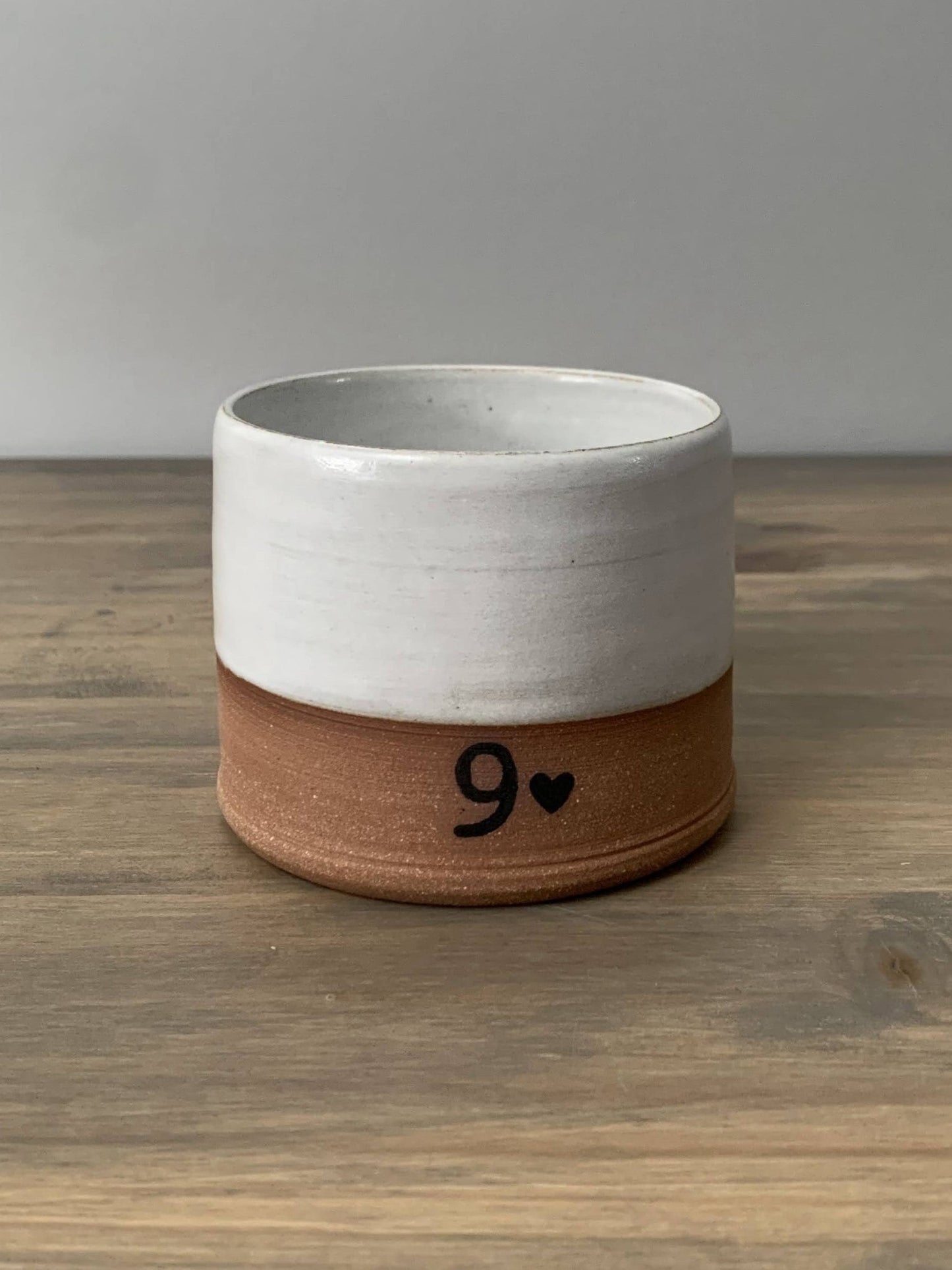 pottery whiskey cup with 9 design on a wooden surface