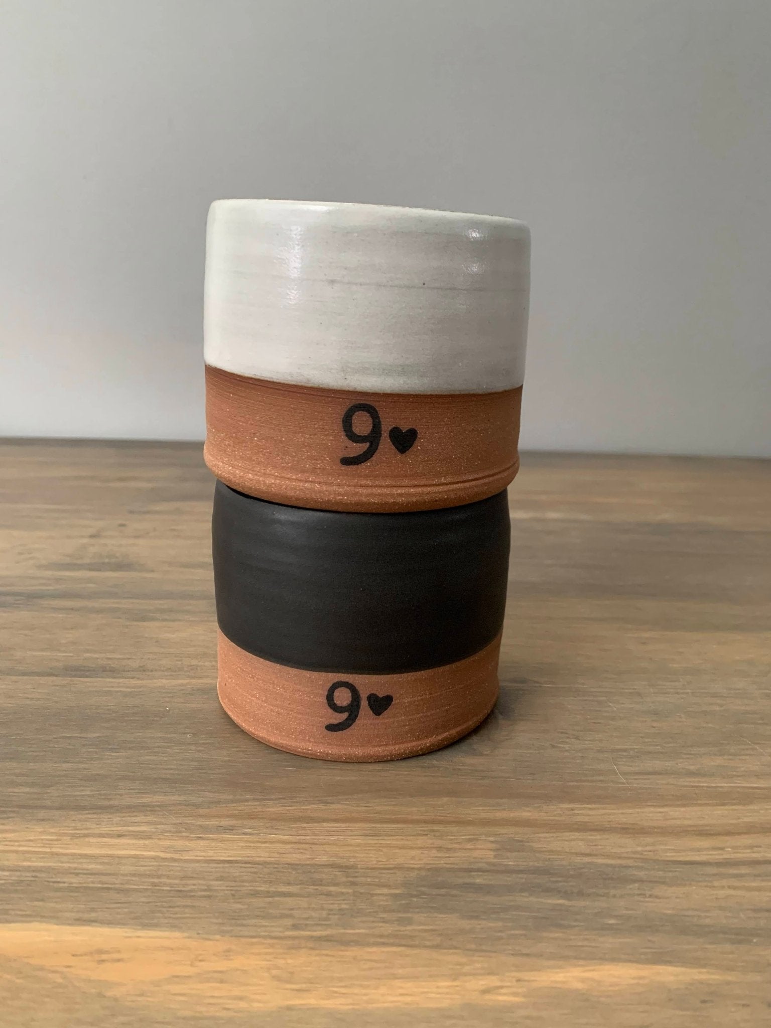 Stack of 2 ceramic whiskey tumblers with number 9 and hearts on a wooden surface