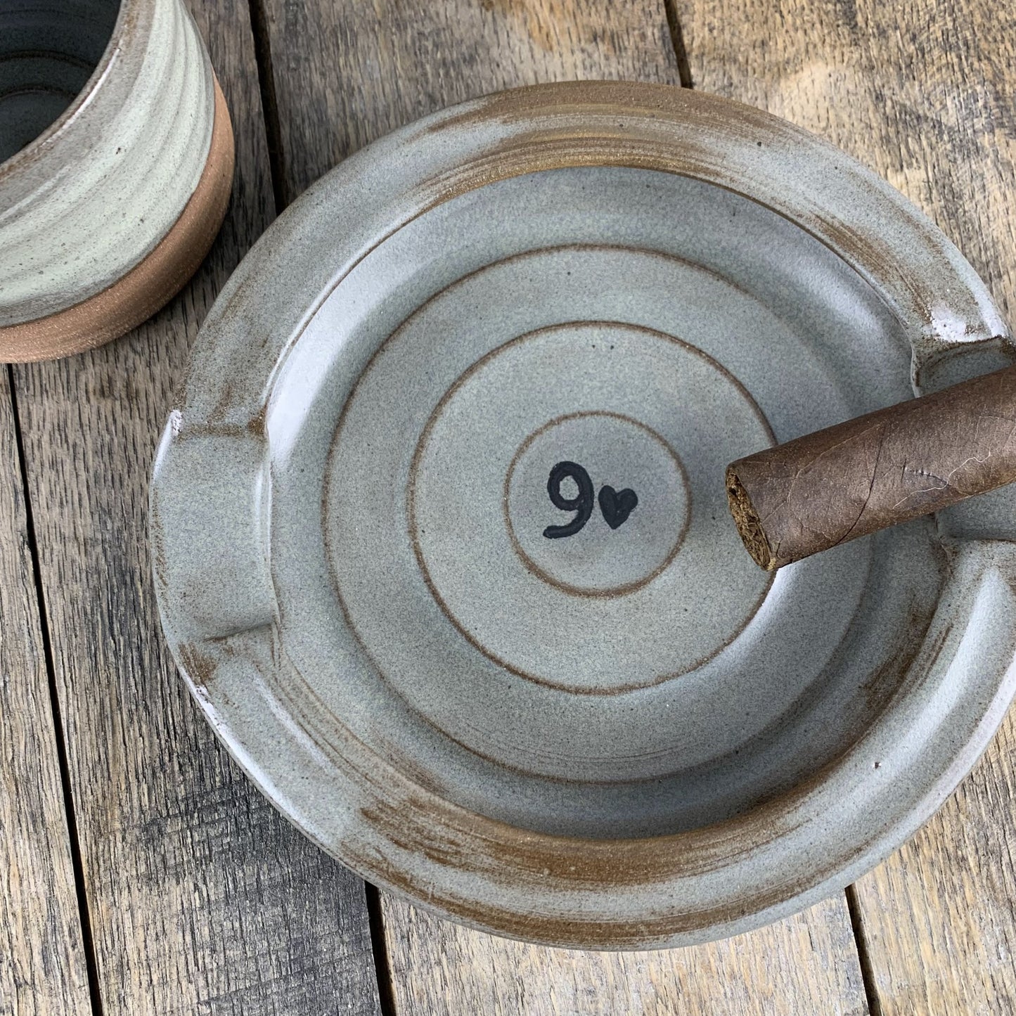 Pottery cigar plate with a heart and number design on a wooden surface