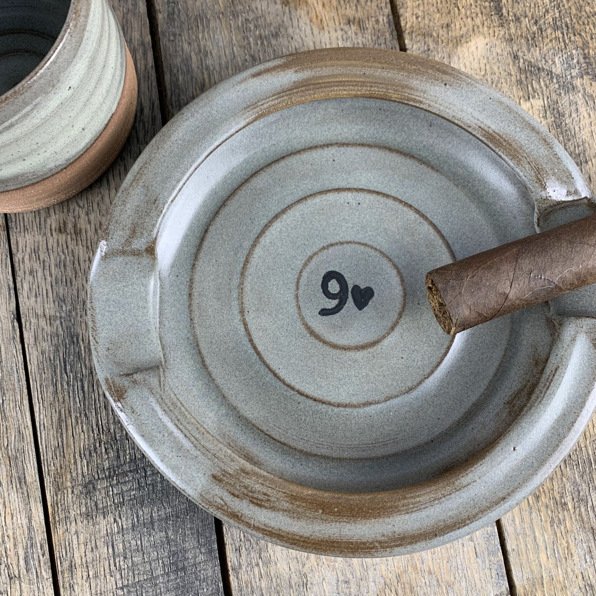 Pottery cigar plate with a heart and number design on a wooden surface