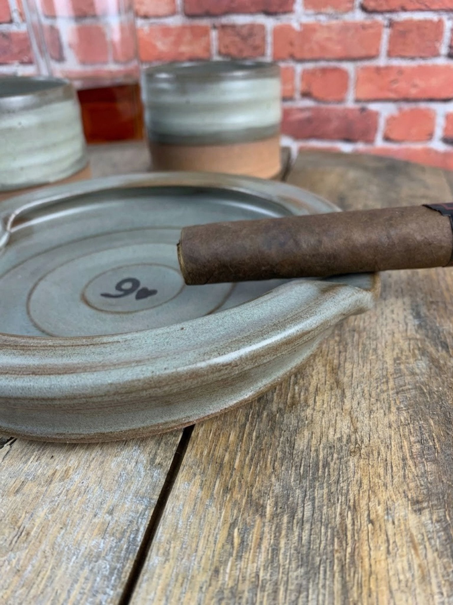 Cigar on a ceramic ashtray with a brick wall background
