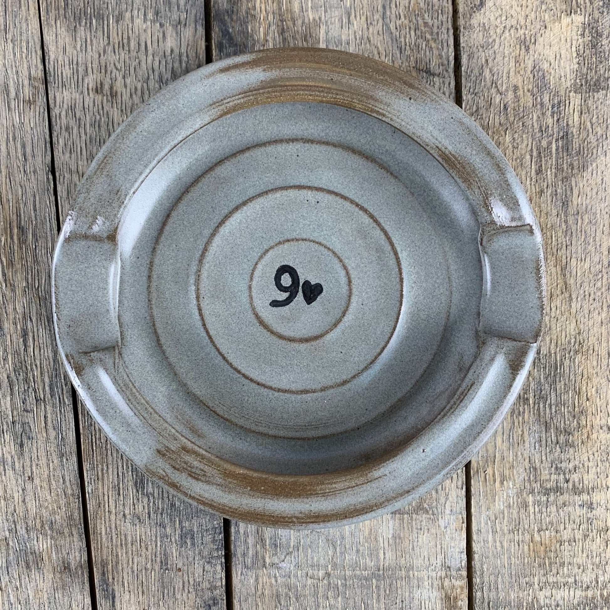 Ceramic pottery ashtray with number 9 on a wooden surface
