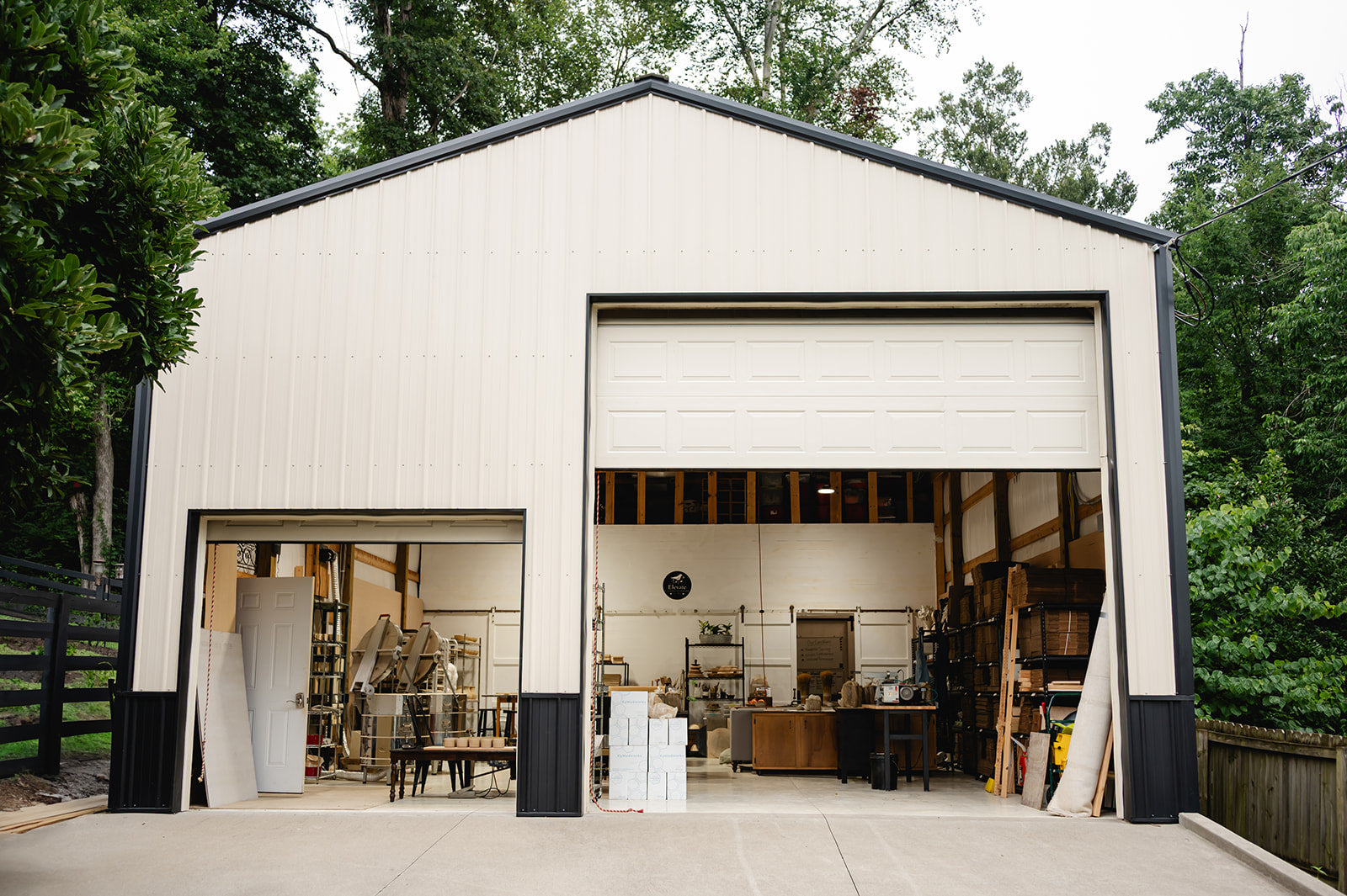 Modern white garage with open doors, surrounded by trees