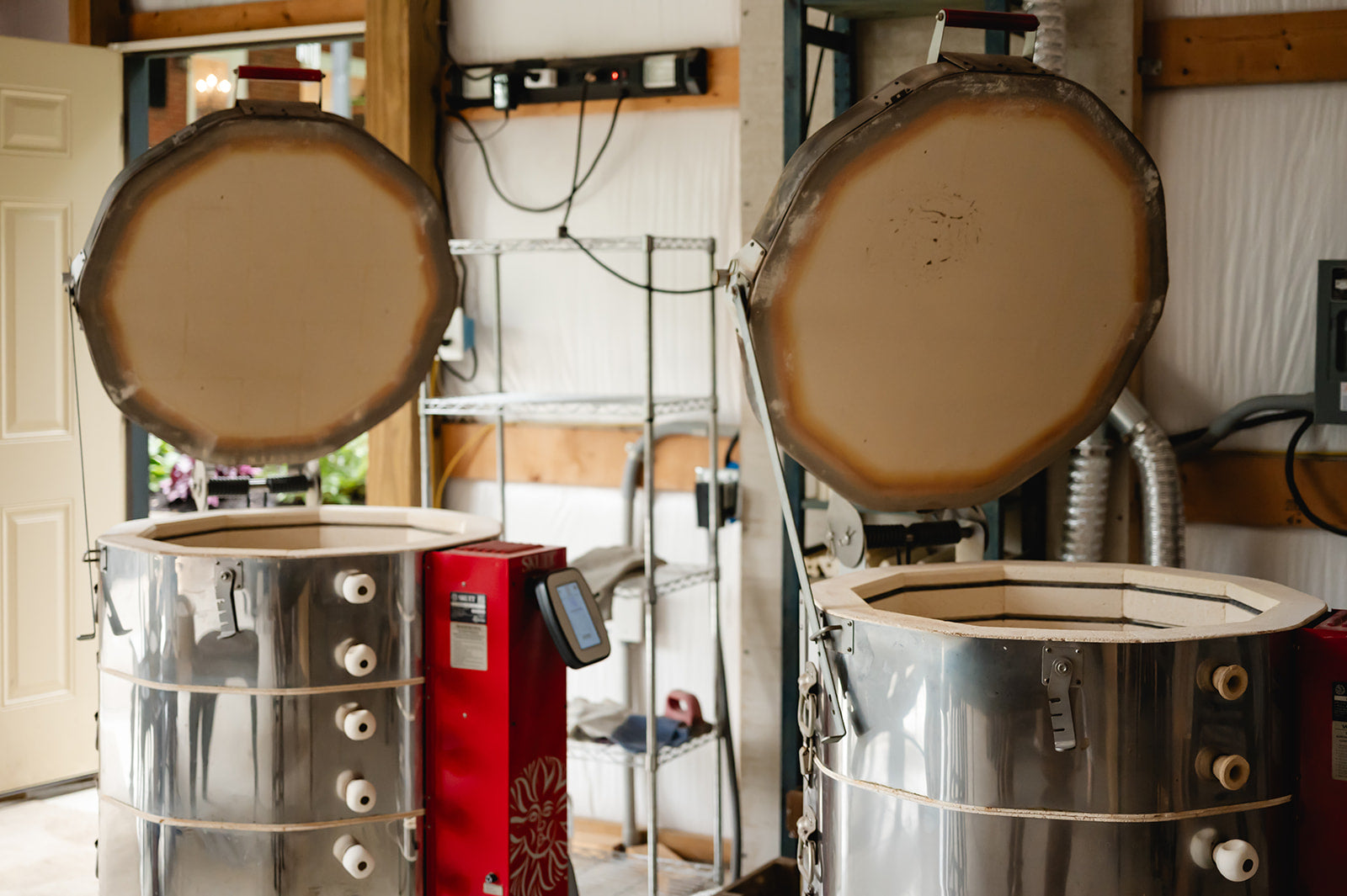 Two large metal ceramic kilns with open tops in a pottery art studio setting.