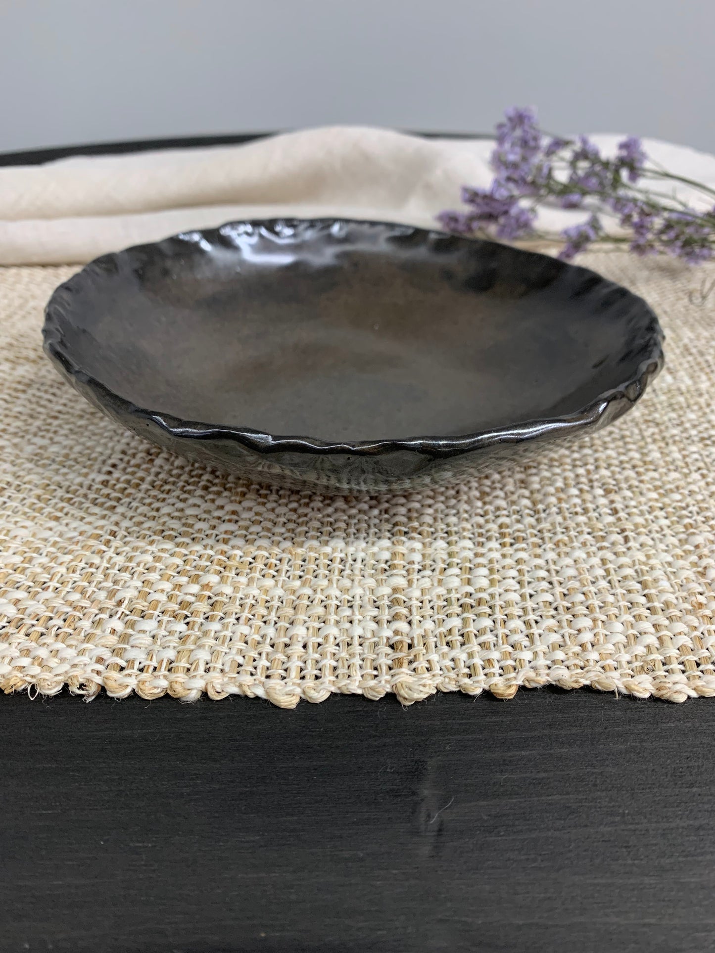 Dark handcrafted ceramic bowl and lavender flowers on a gray background