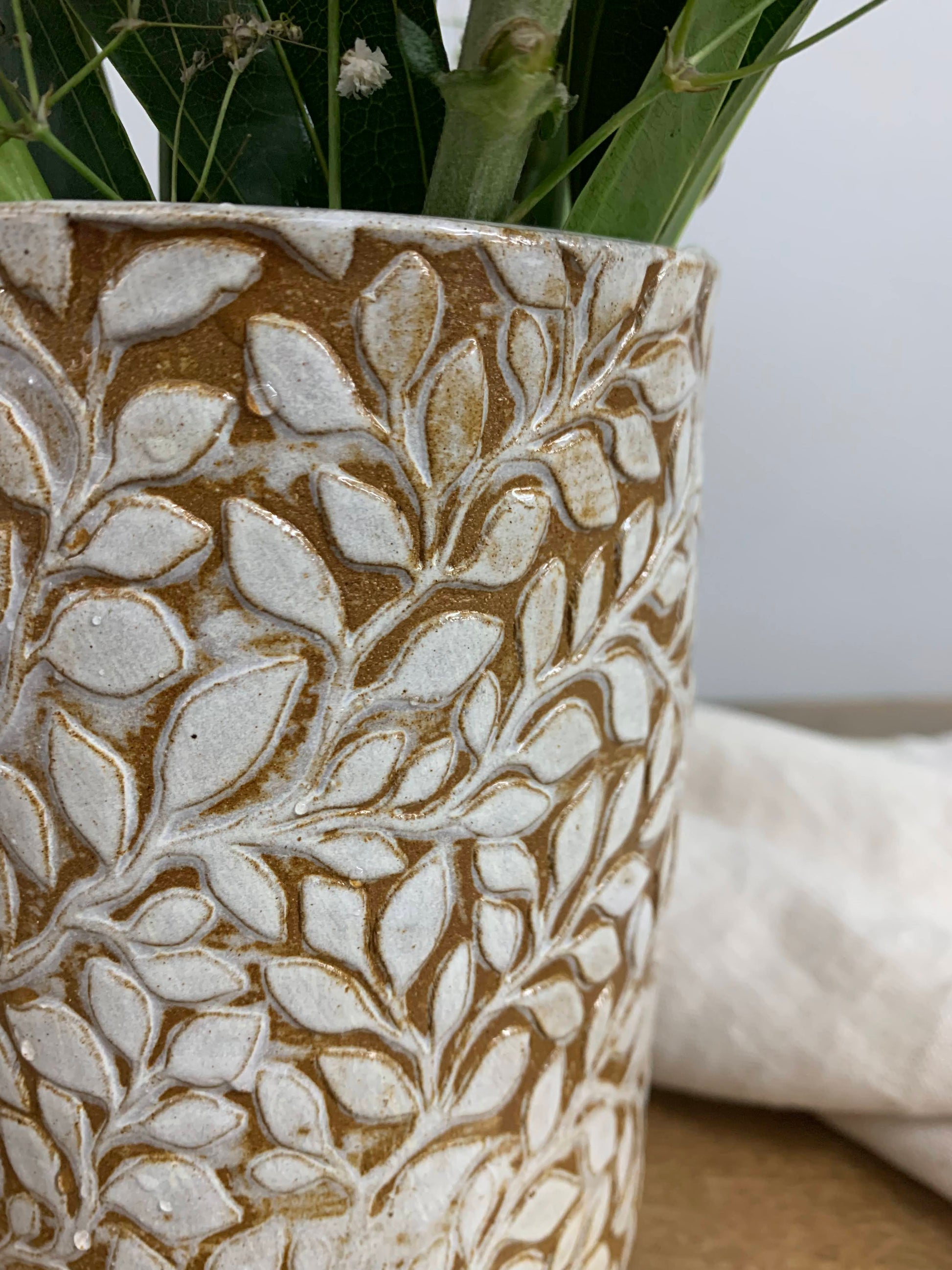 closeup of Decorative stoneware vase with leaf pattern on a neutral background