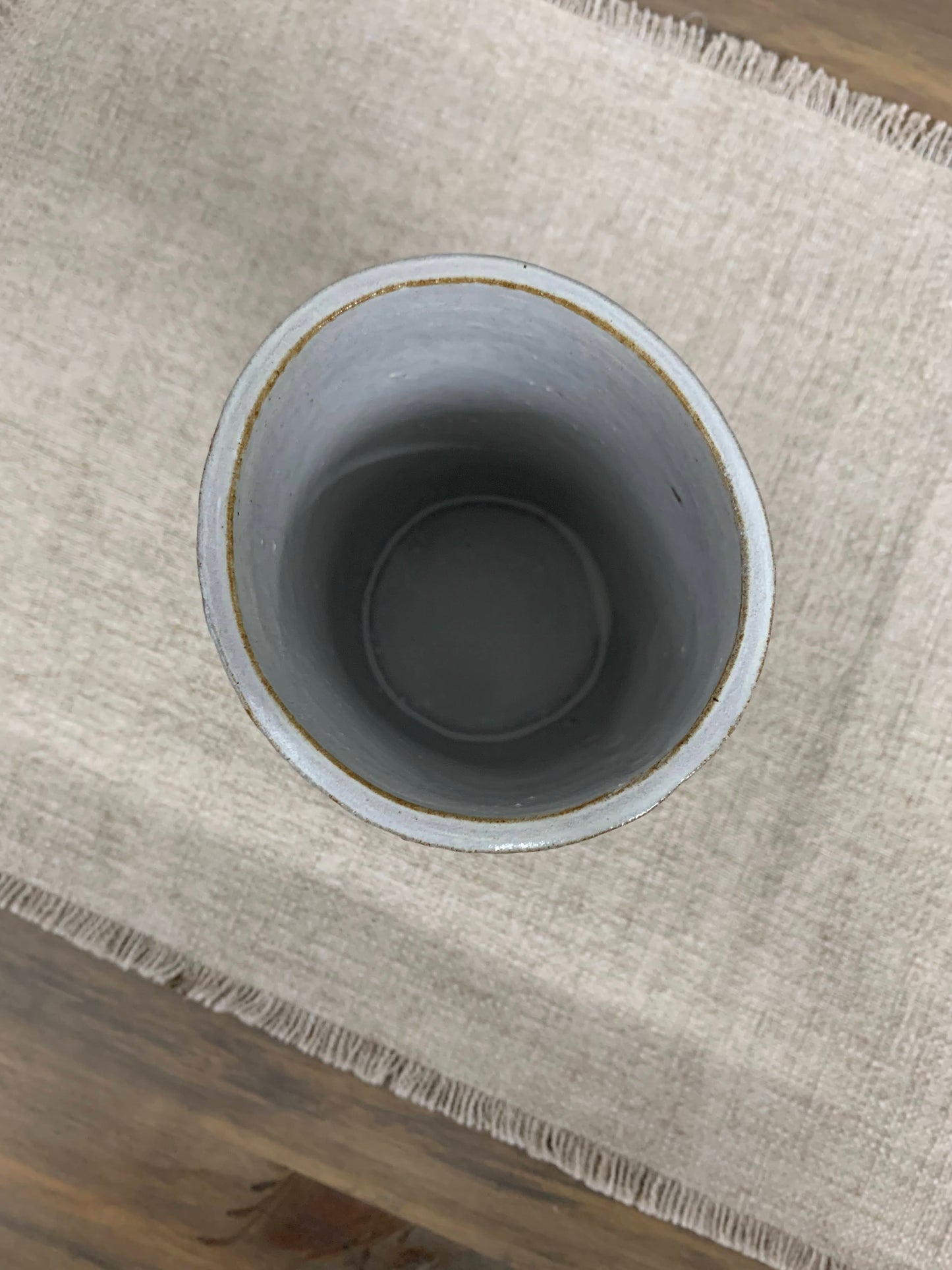 Gray ceramic vase from the top on a textured beige surface