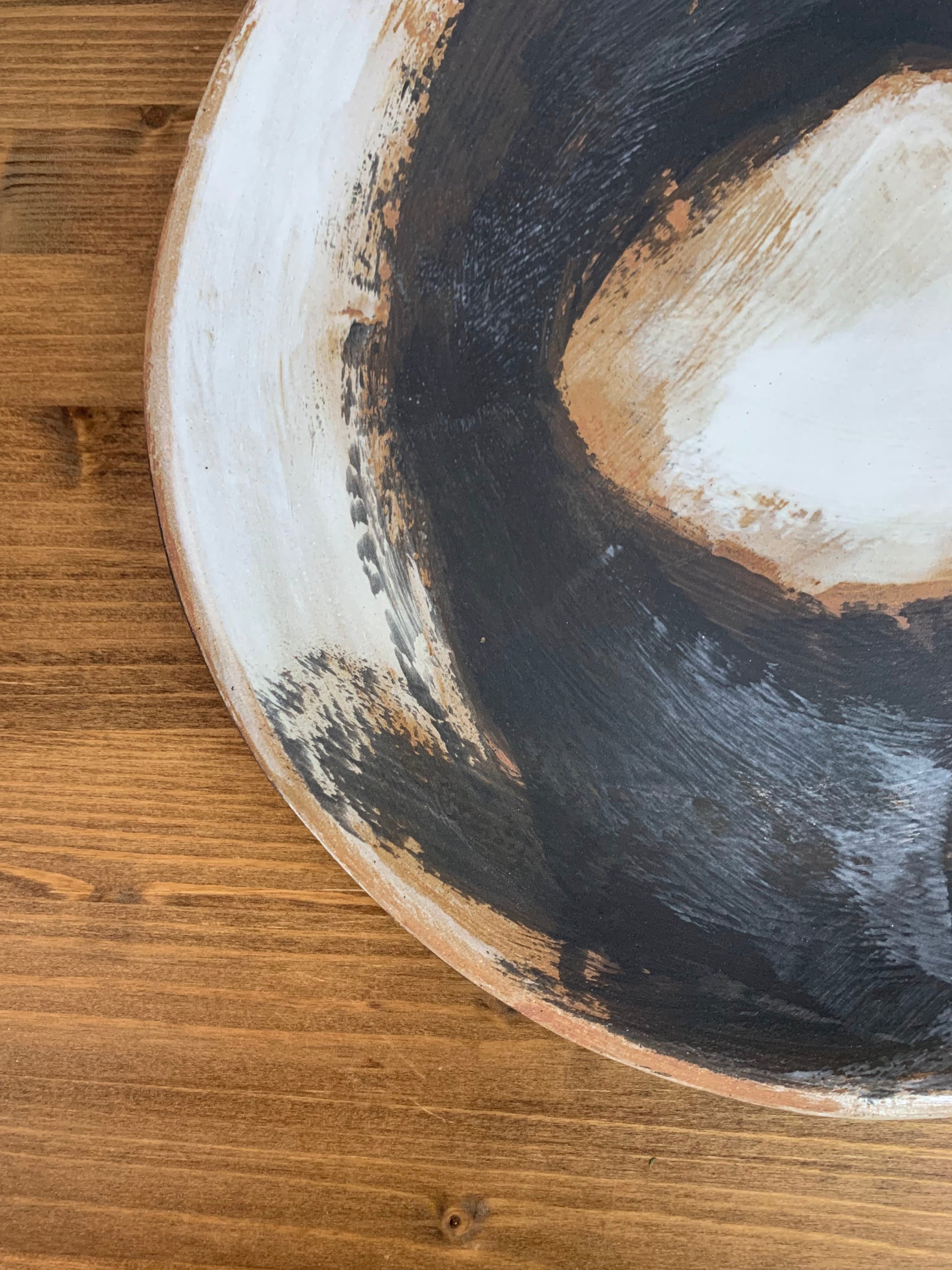 Close-up of a ceramic art platter with concentric circular patterns in black, white, and brown.