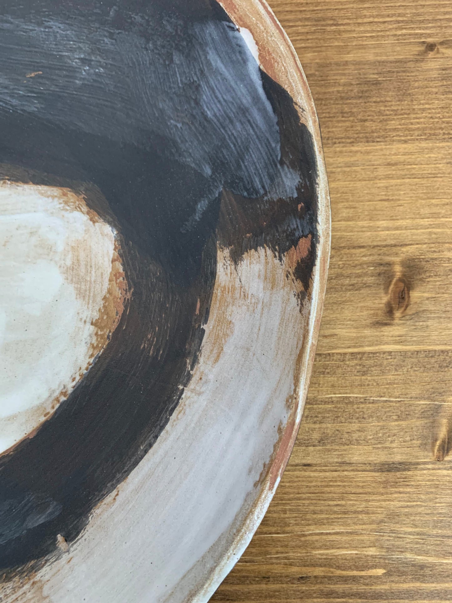 Close-up of a ceramic art platter with concentric circular patterns in black, white, and brown.
