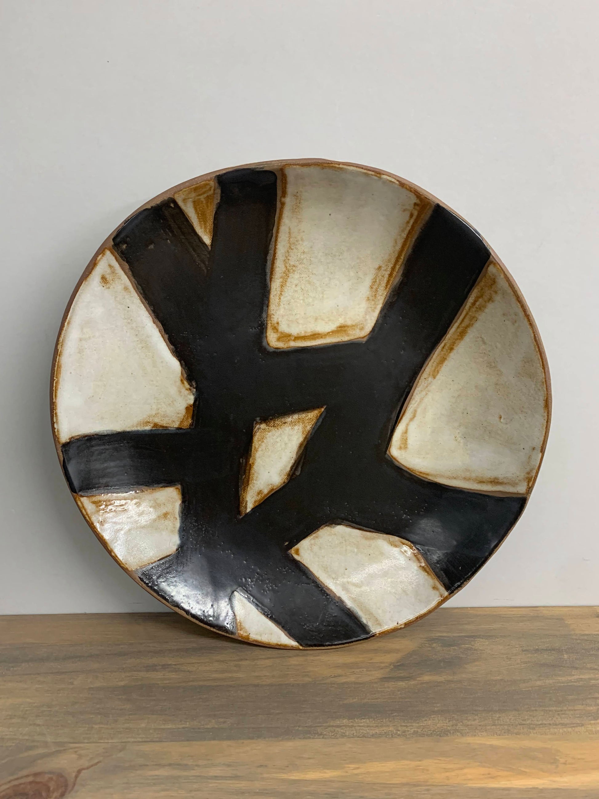 Handcrafted ceramic art plate with black and white abstract design on a light gray background