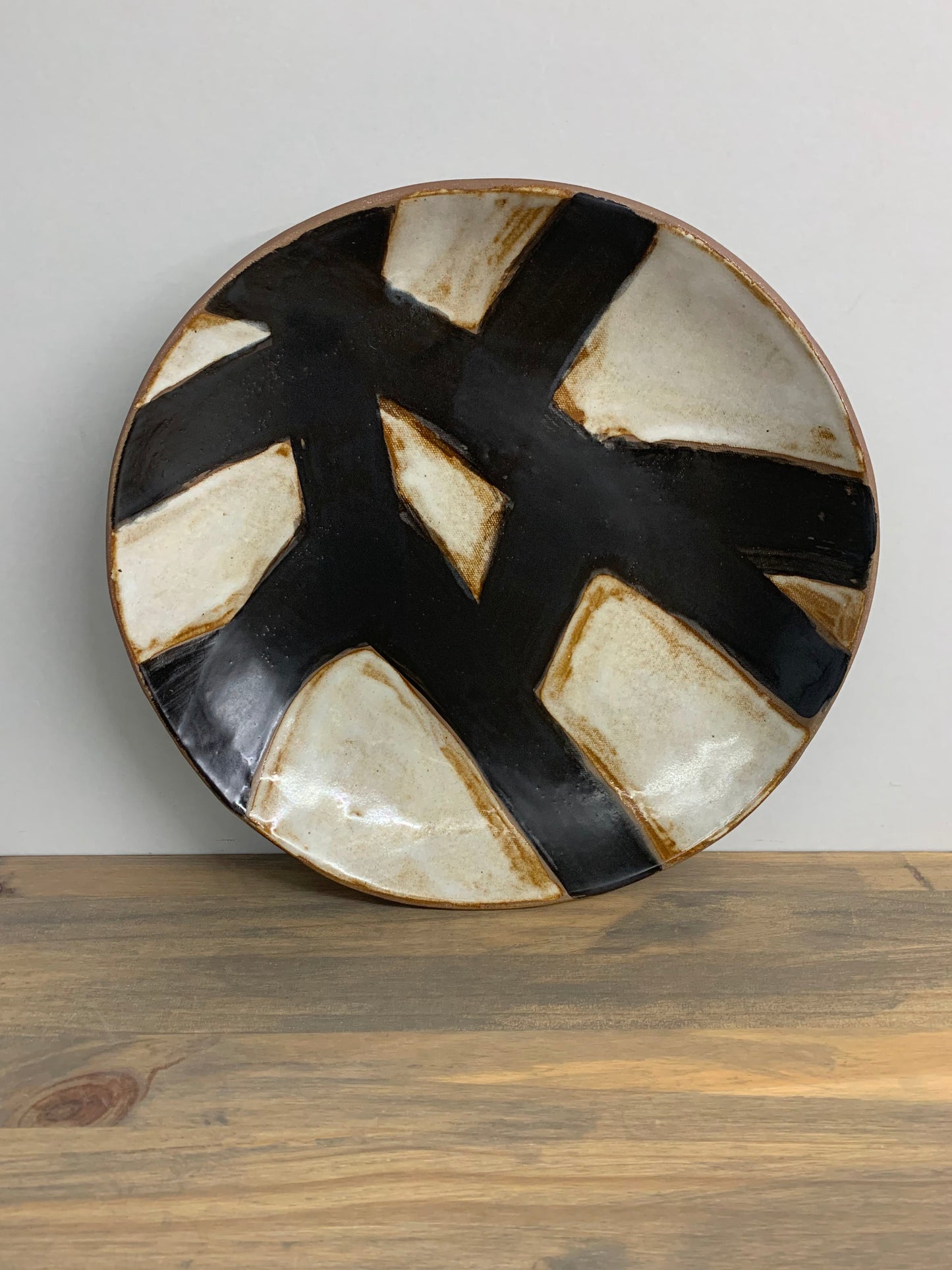 Decorative ceramic art plate with black and white abstract design on a light gray background