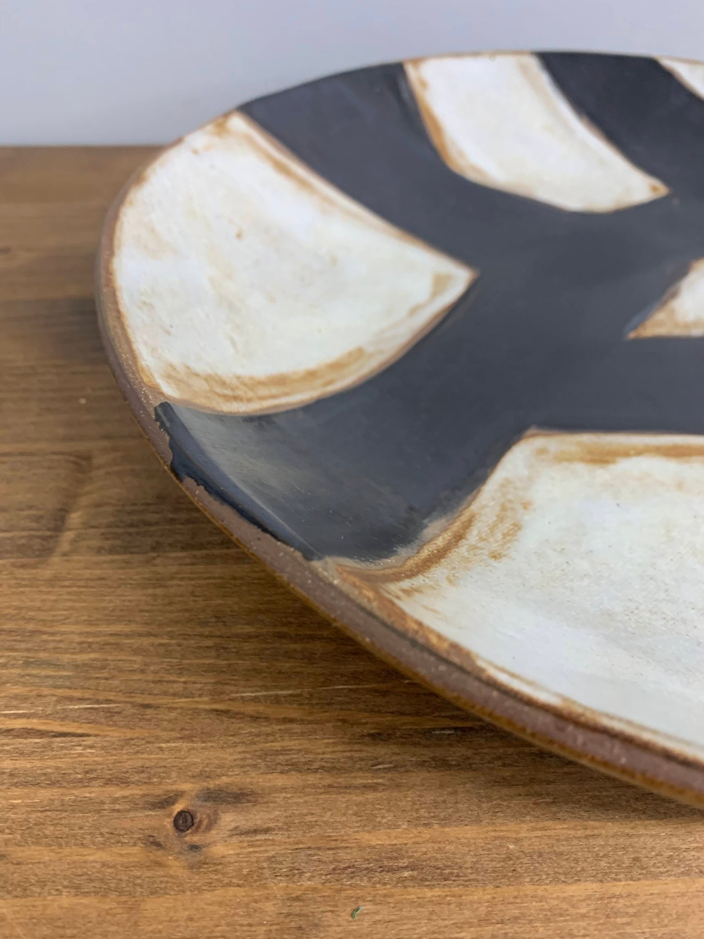 Close-up of a ceramic plate with black and white abstract design on a wooden surface.