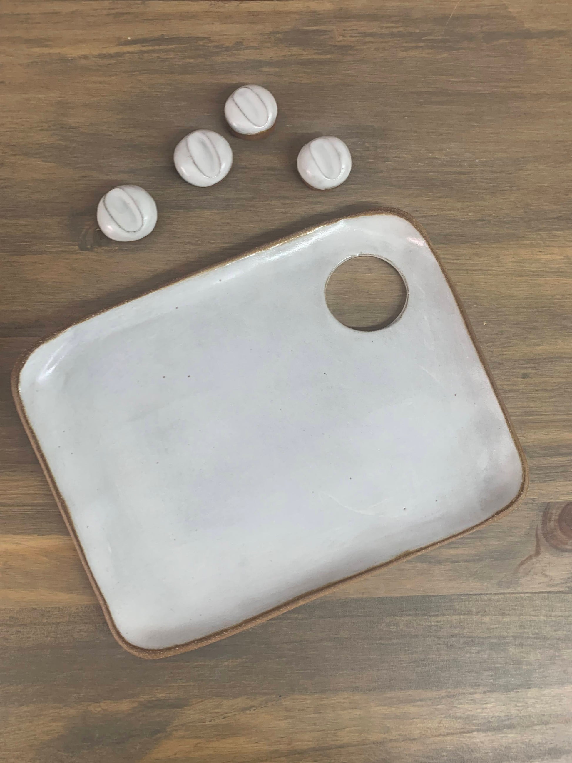 White ceramic paint tray palette with a circular hole on a wooden surface