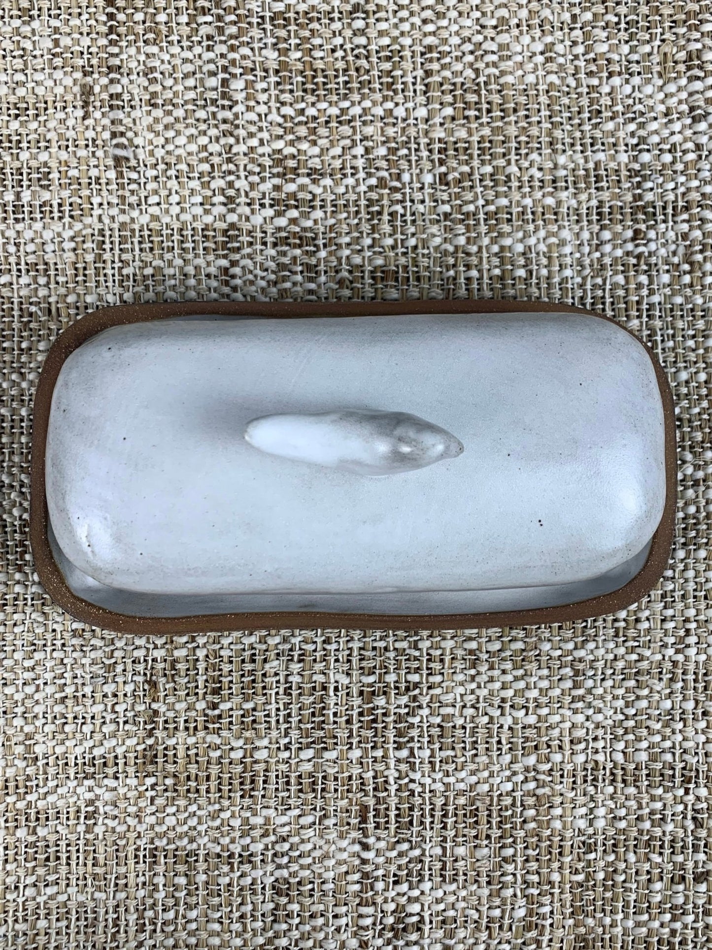 Rectangular ceramic dish with brown rim on a textured beige fabric background
