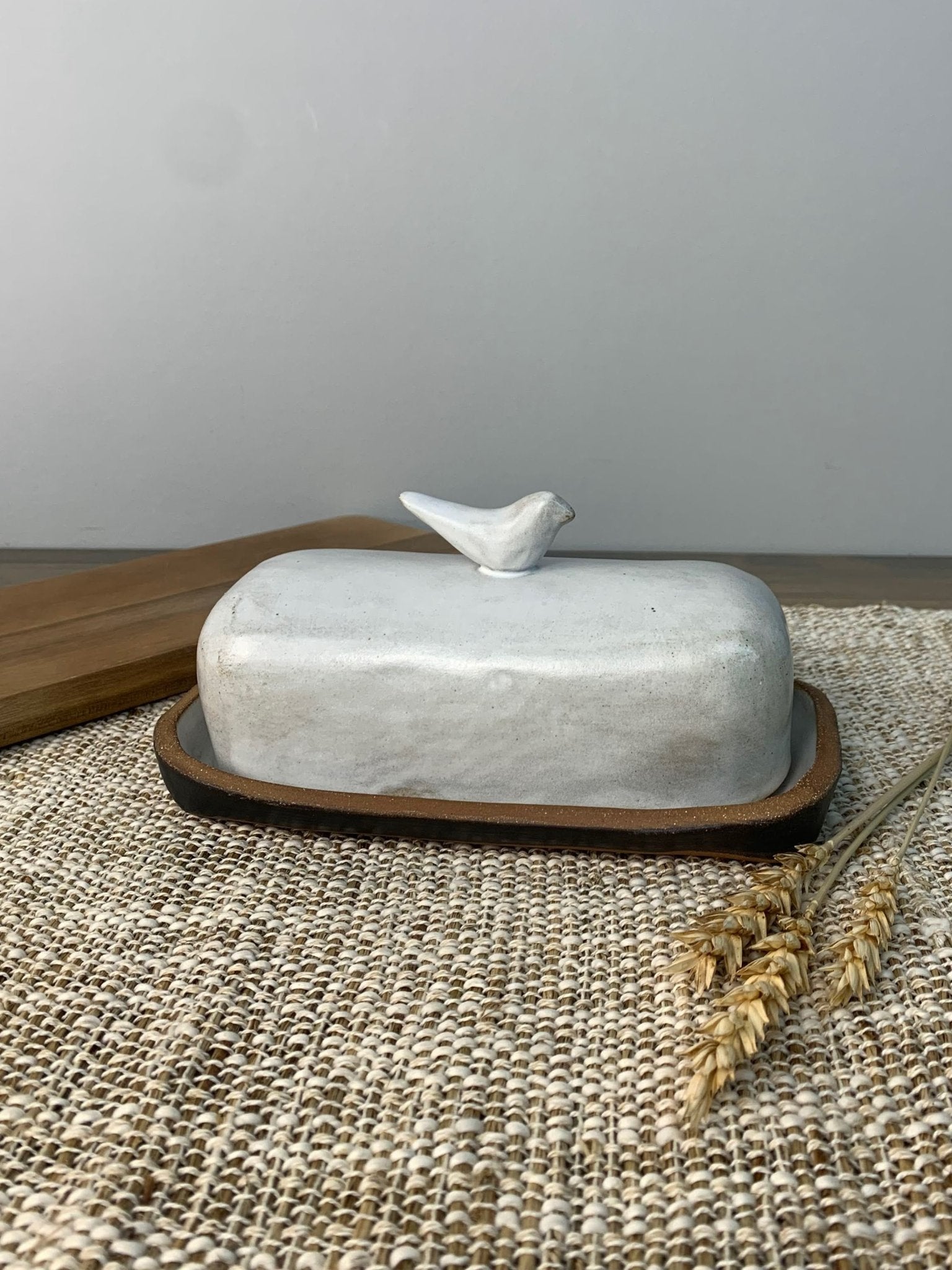 White handmade ceramic butter dish on textured surface