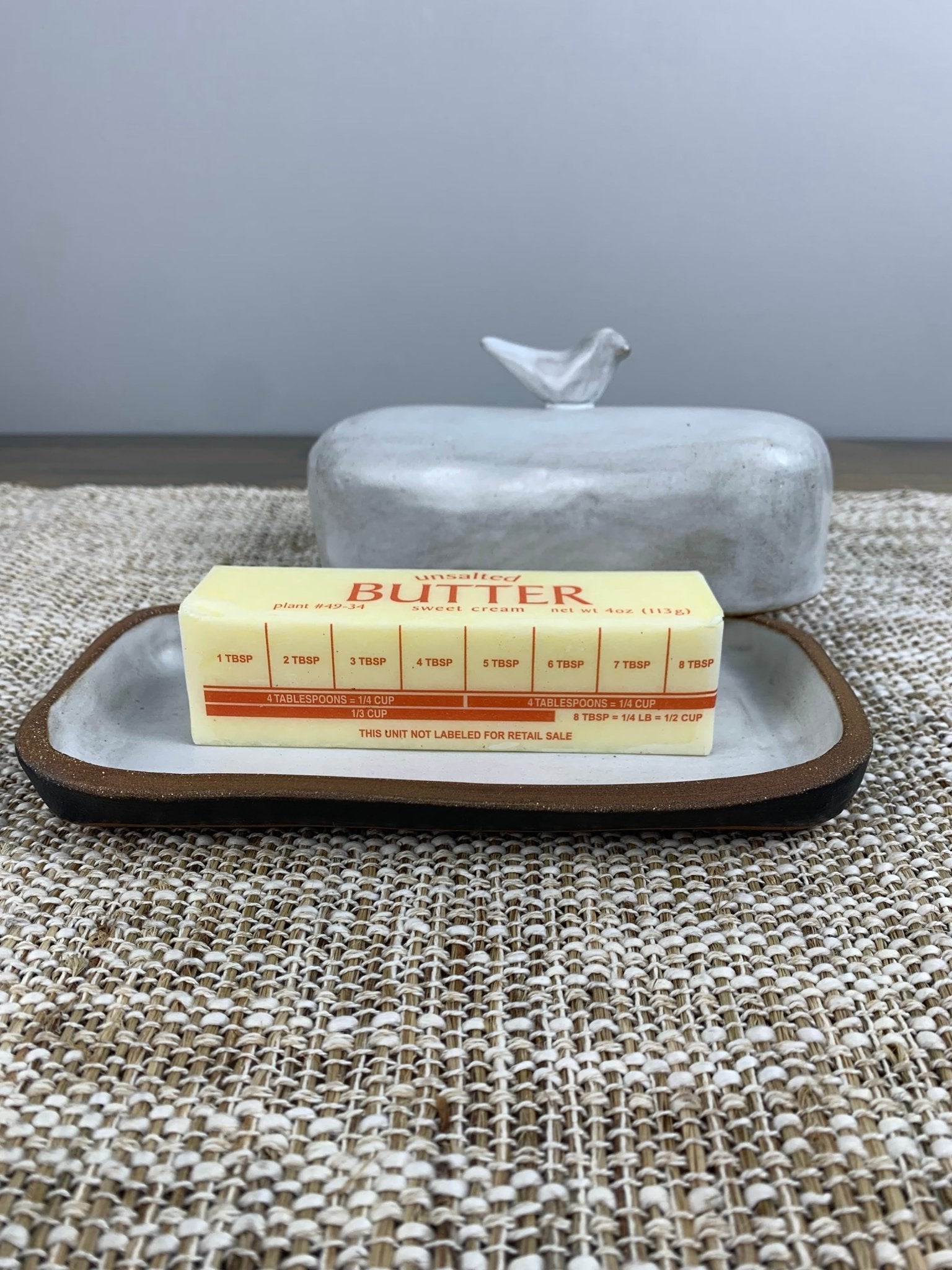 Handmade ceramic butter dish with a block of butter on a textured surface