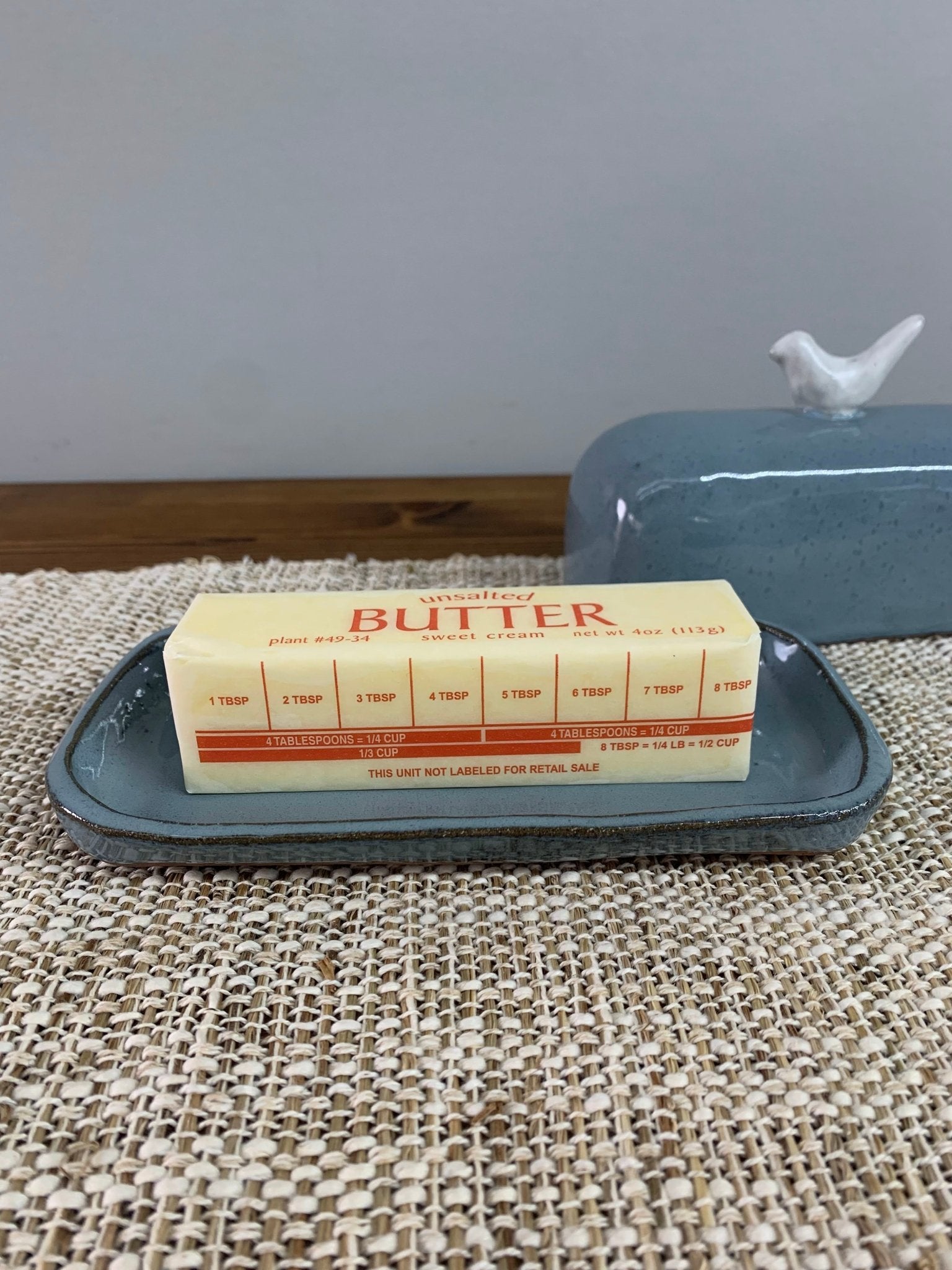 Butter stick on a butter dish tray that is blue and handmade stoneware