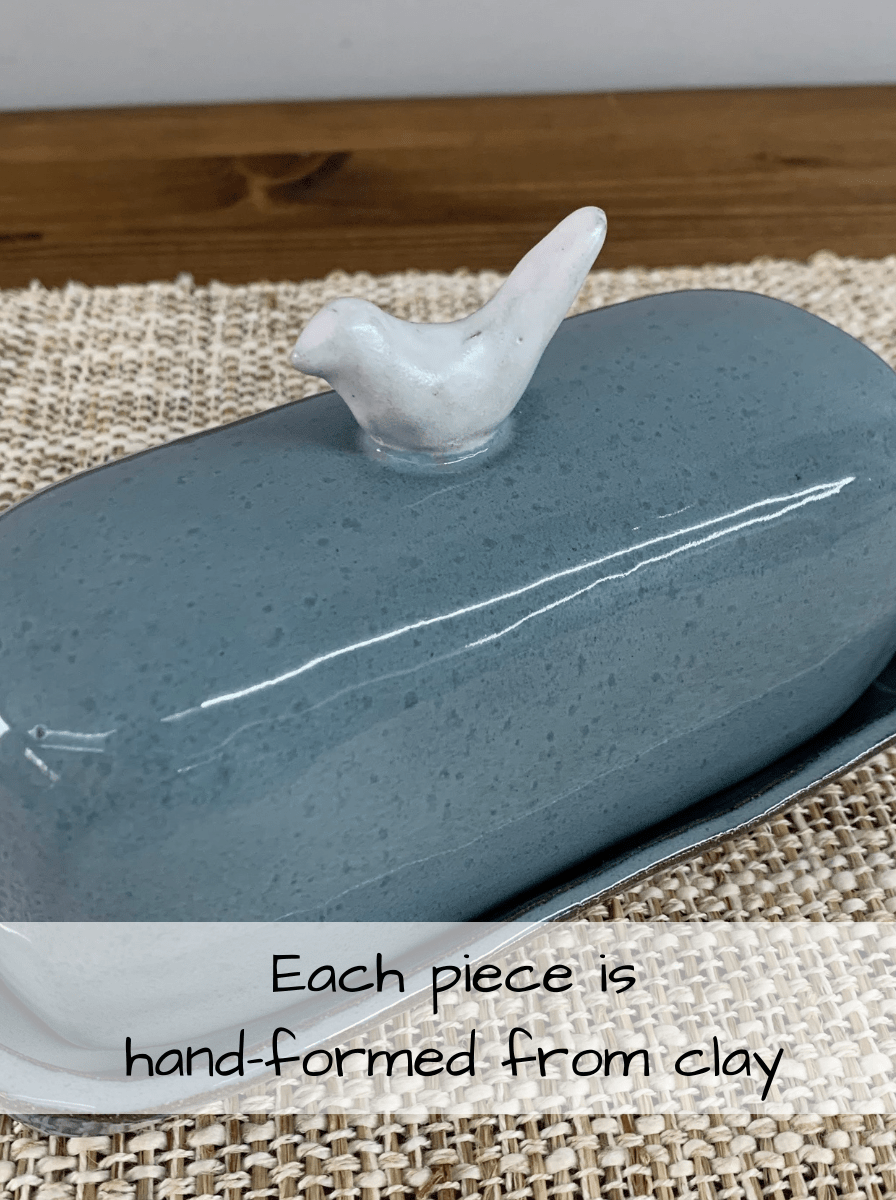 Blue ceramic butter dish with a white bird figurine on a woven mat