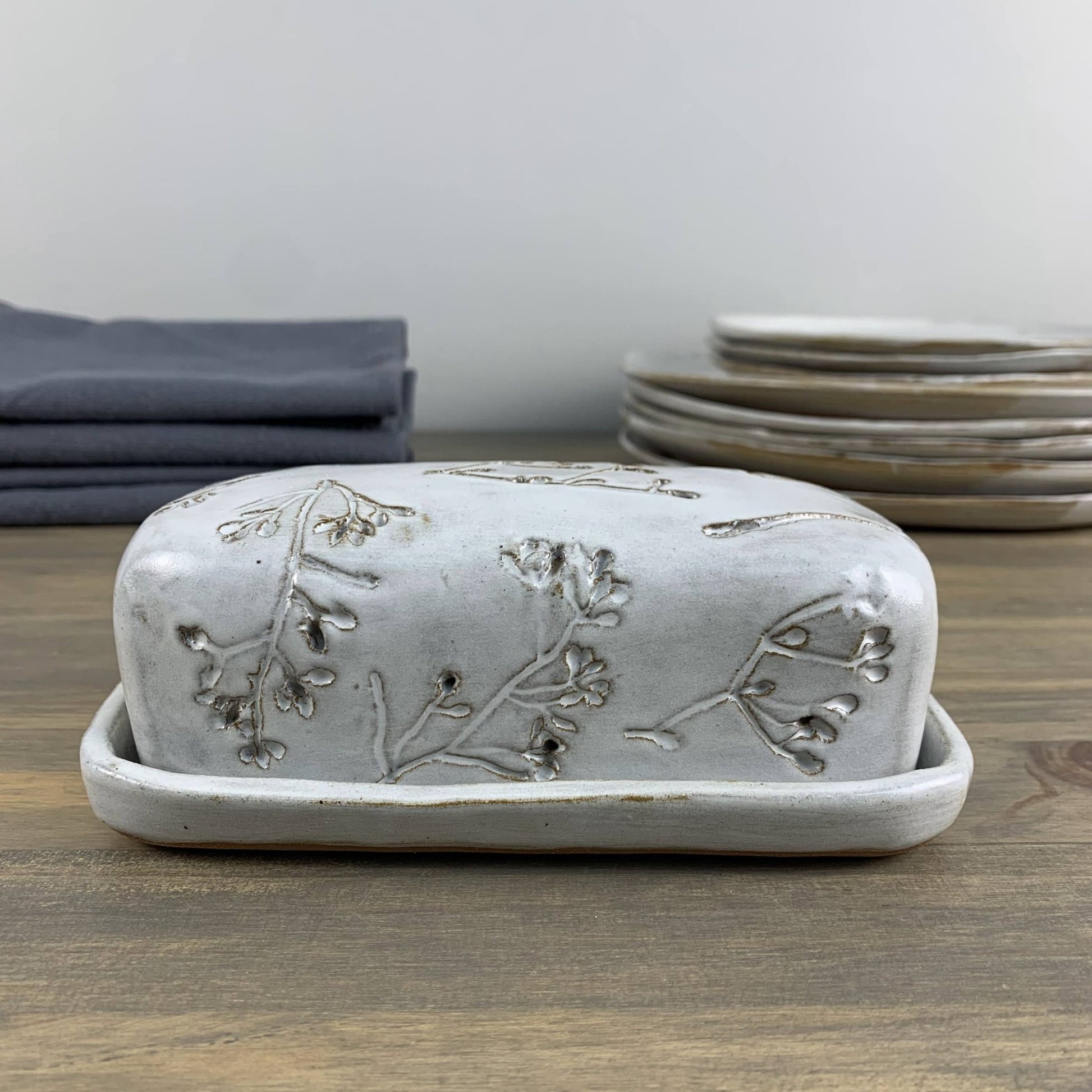 Handmade ceramic butter dish with floral patterns on a wooden surface