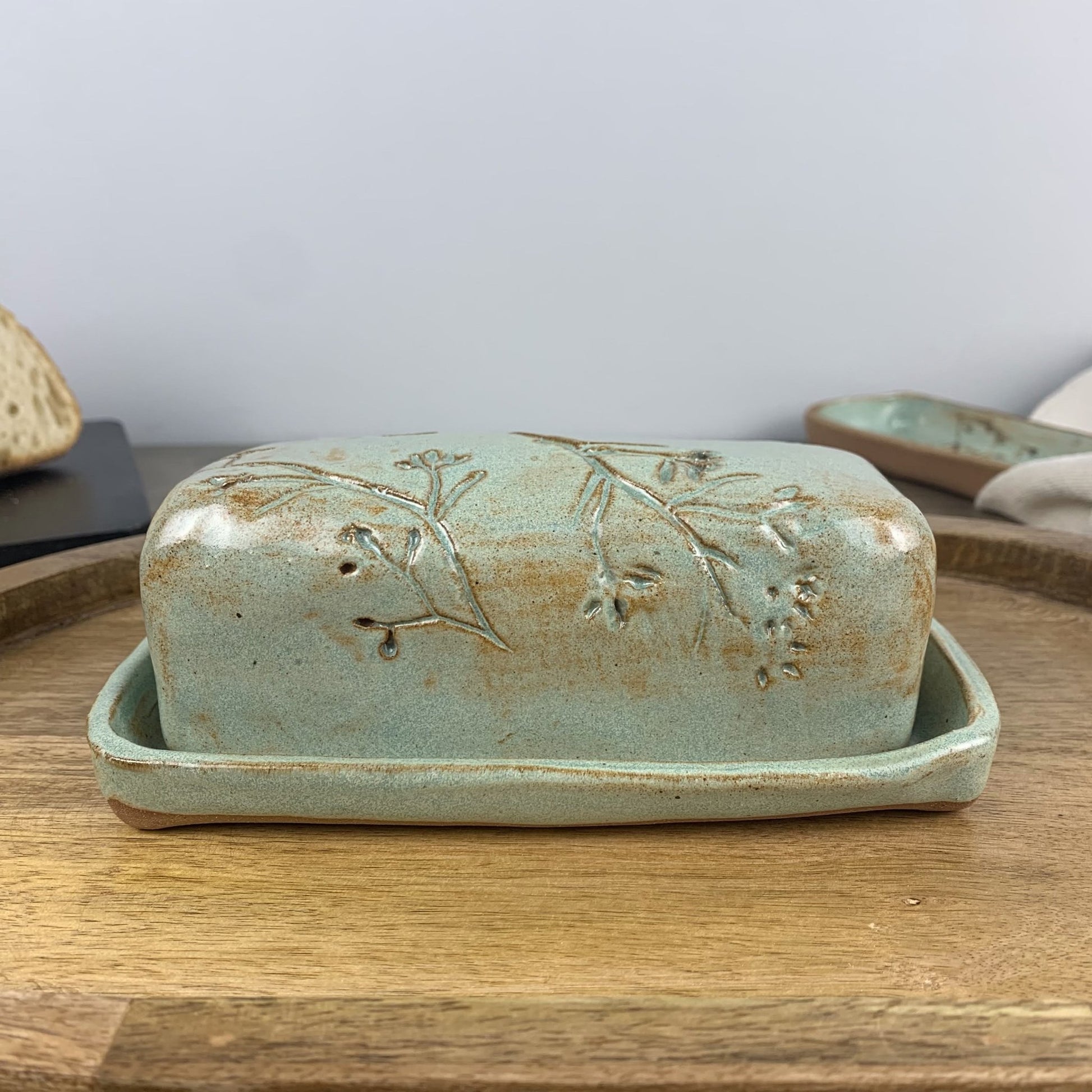 Handmade ceramic butter dish with lid on a wooden surface