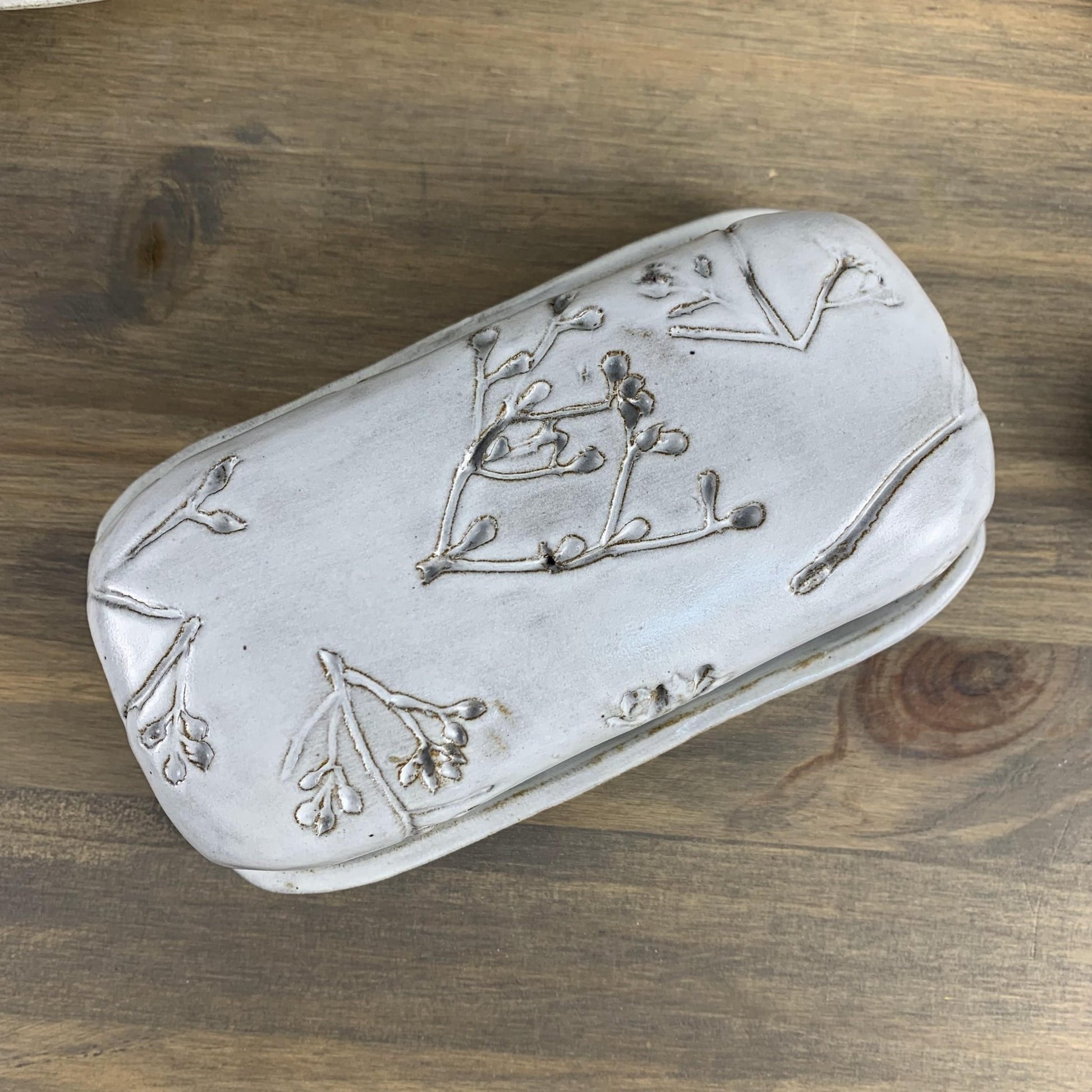 White handmade ceramic butter dish on a wooden surface