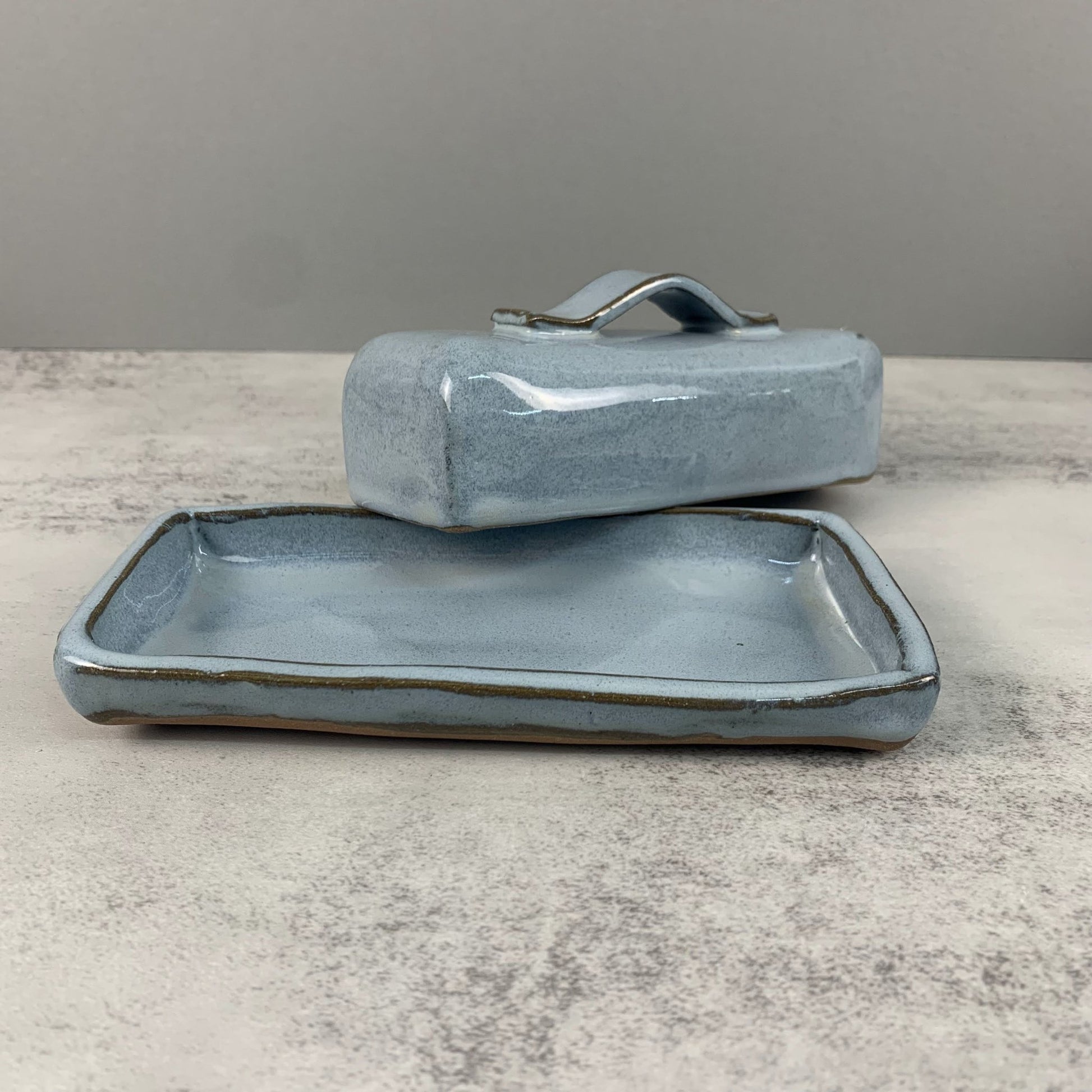 Handmade ceramic butter dish on a gray surface with a neutral background