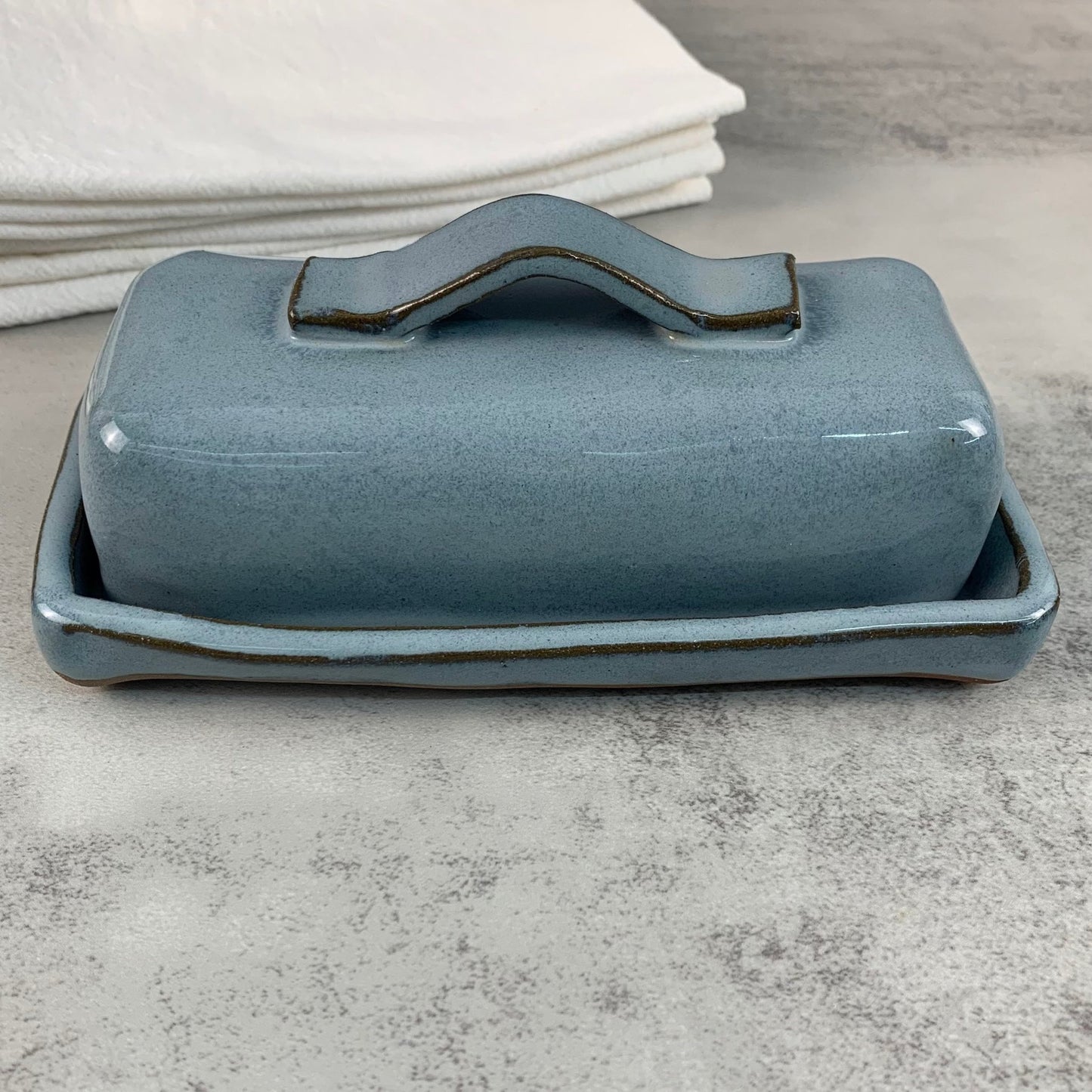 Blue ceramic butter dish with handle on a gray surface
