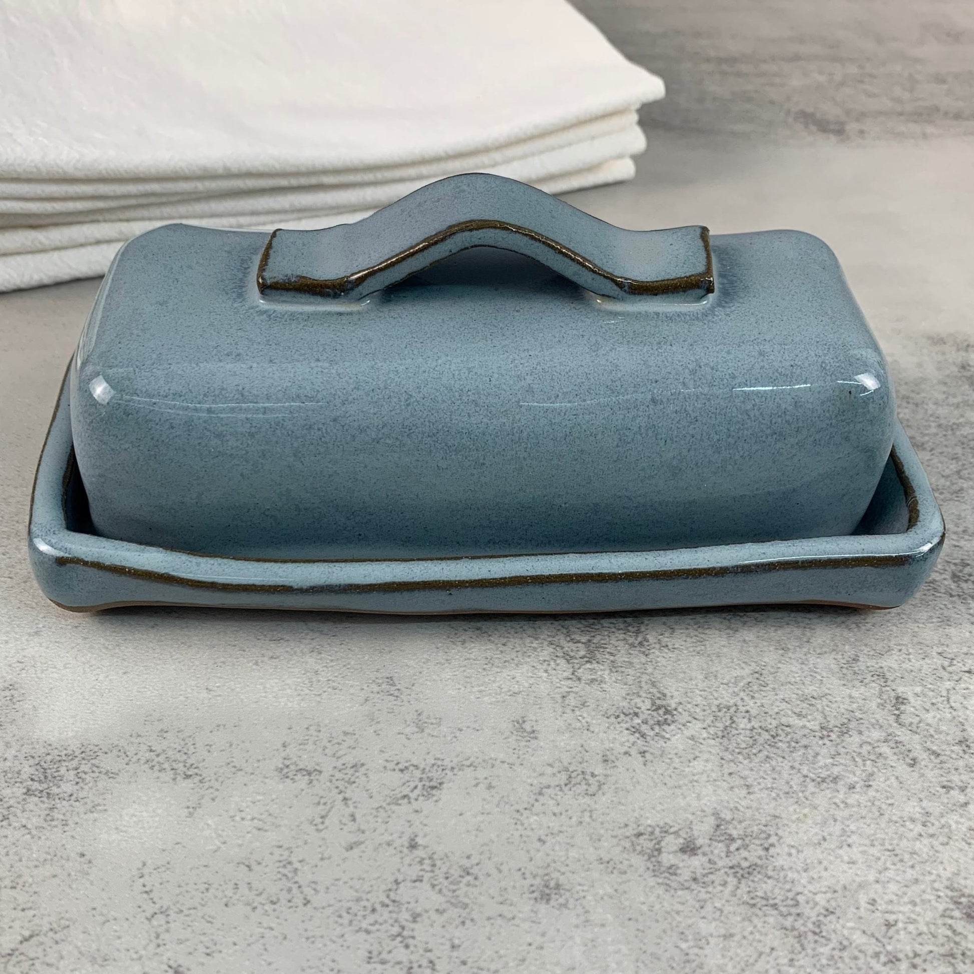Blue ceramic butter dish with handle on a gray surface