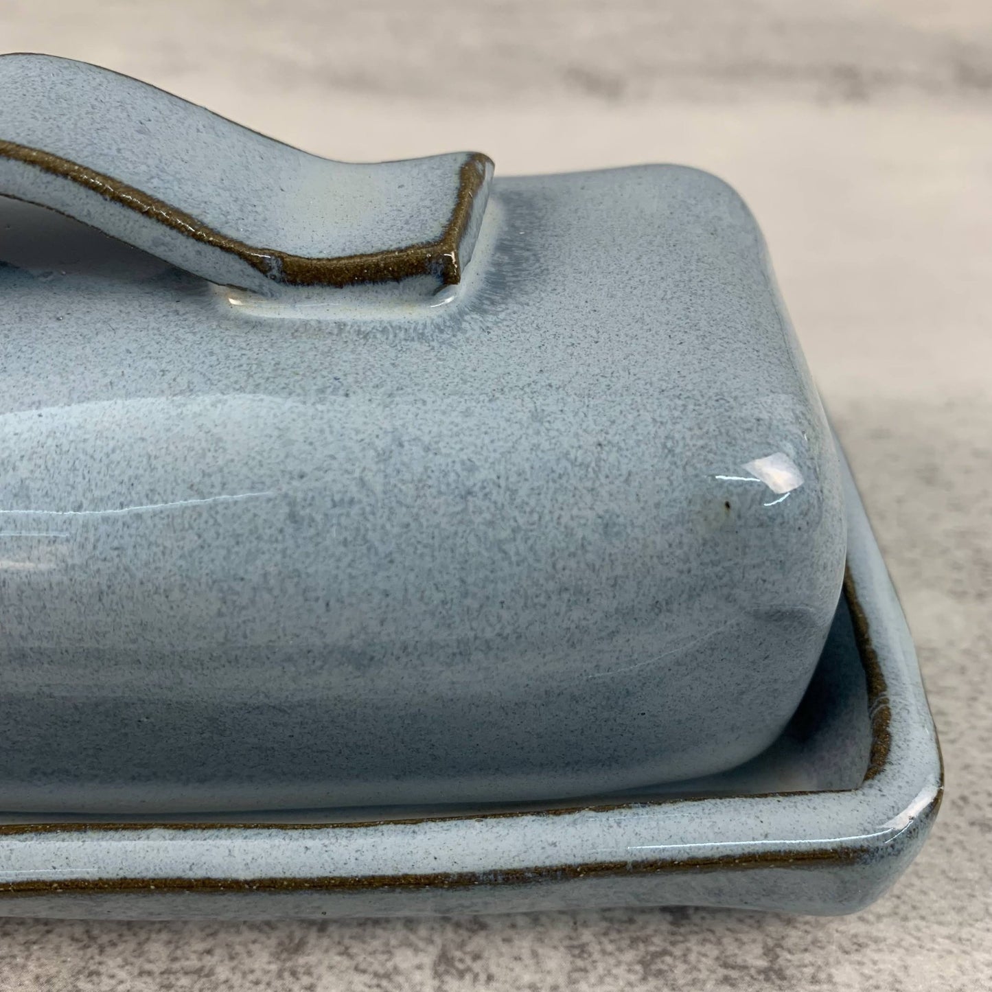 Blue ceramic butter dish with handle on a gray surface