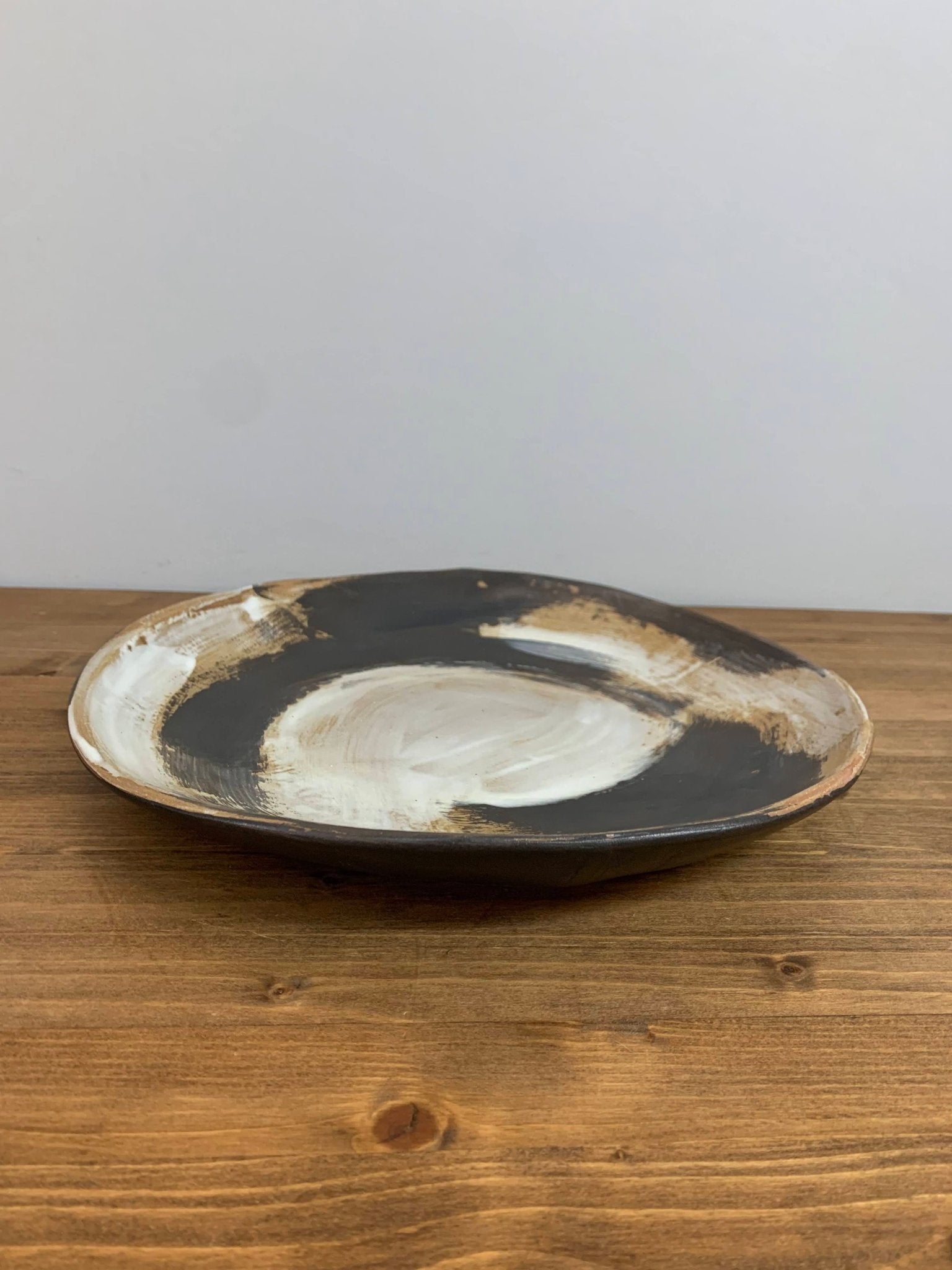 Ceramic art bowl with expressive black and white brush strokes  on a wood surface