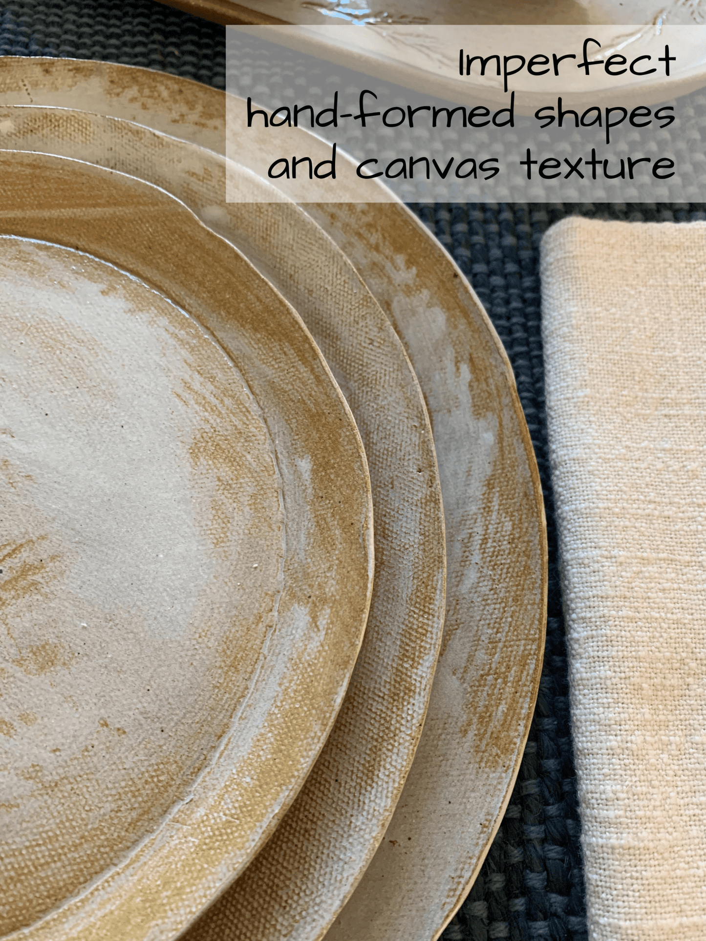 Stack of ceramic plates with textured surface on a dark woven surface