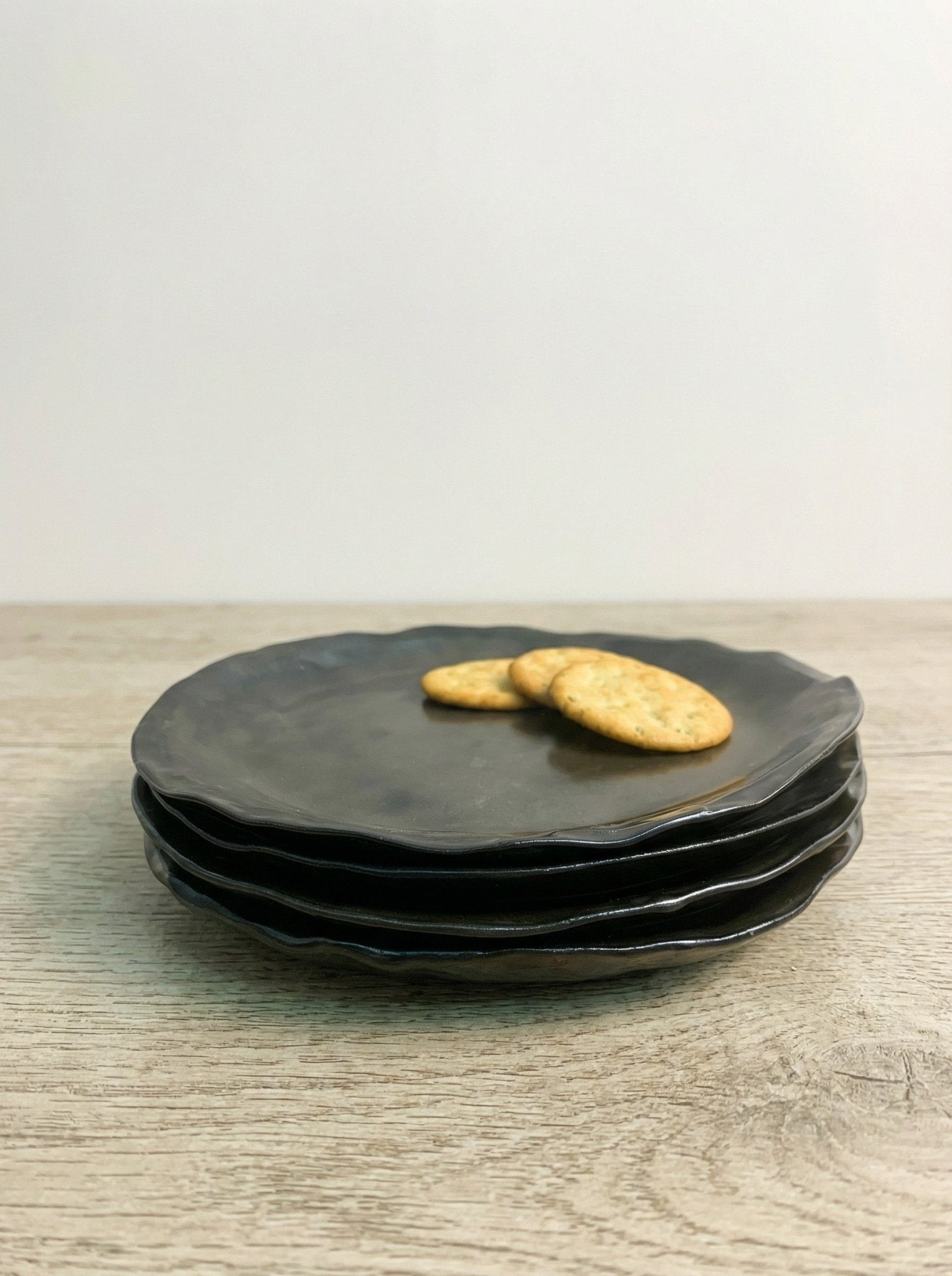 Stack of brown ceramic plates with cookies on a wooden surface