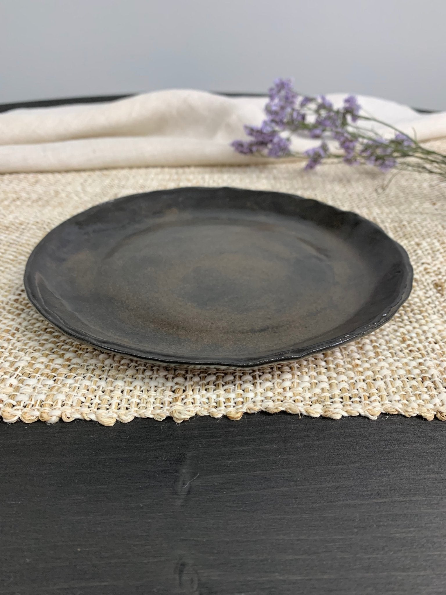 brown handmade ceramic plate on a textured surface with a light background