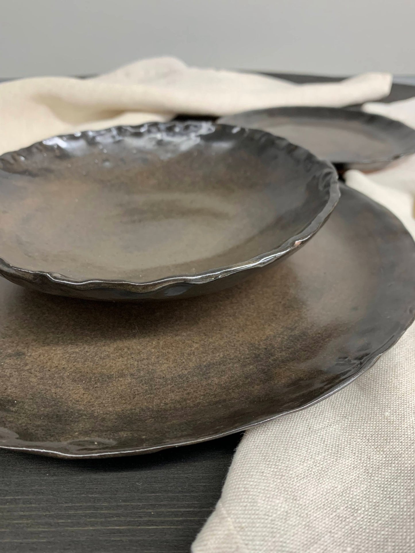Set of dark stoneware ceramic plates on a neutral background
