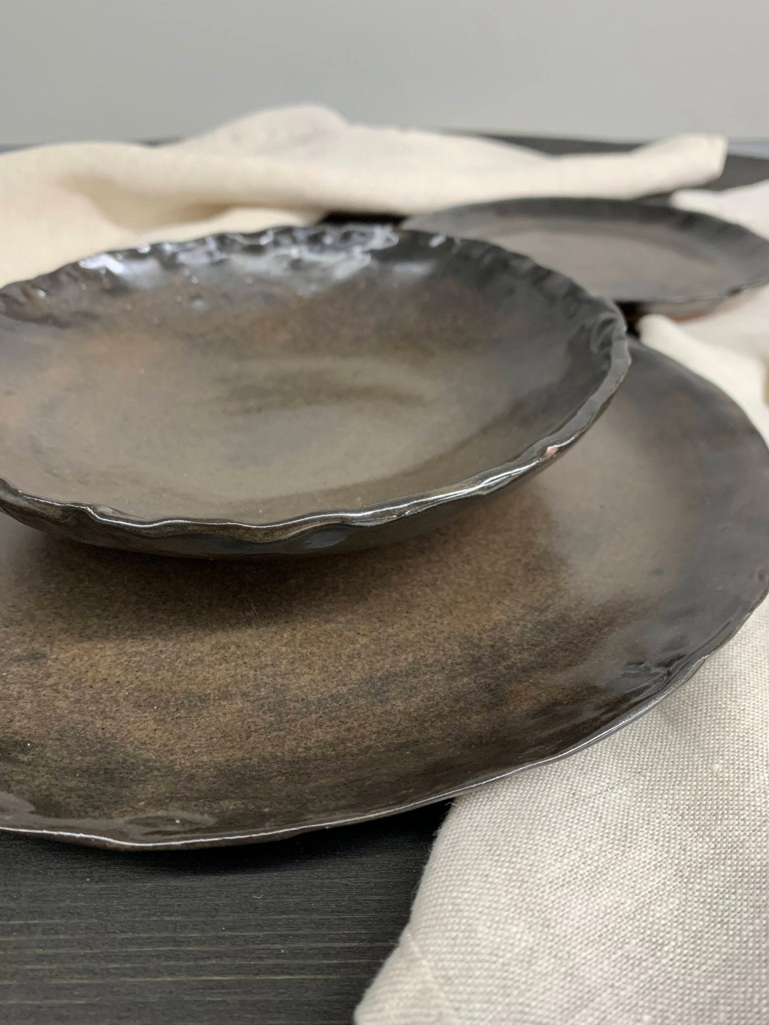 Set of dark stoneware ceramic plates on a neutral background