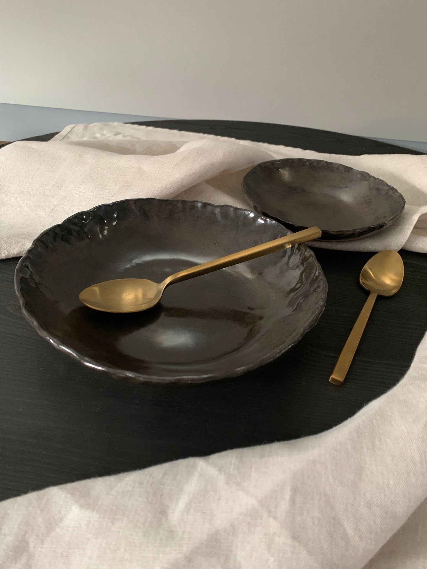 Black ceramic plates with gold spoons on a white cloth